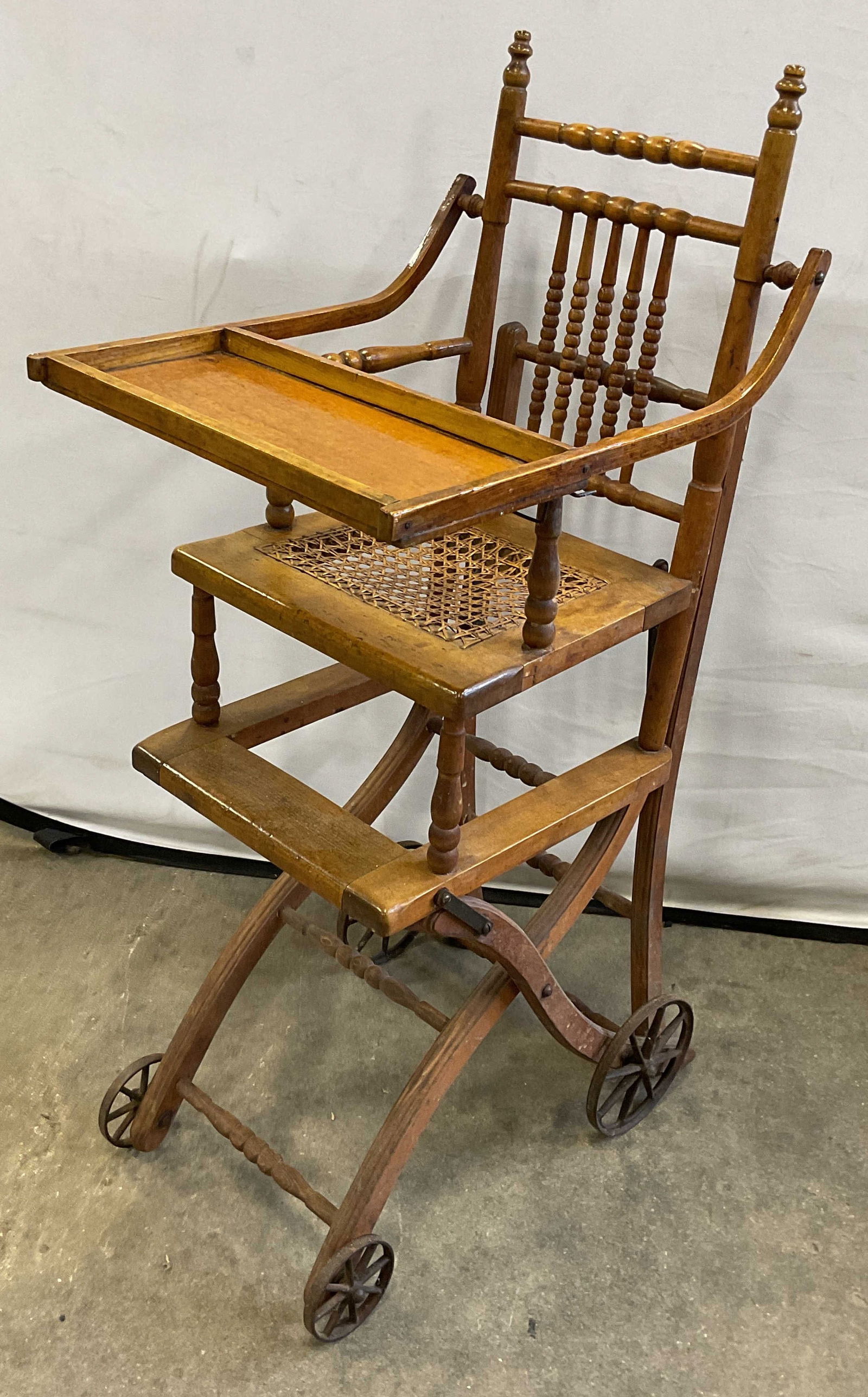 Antique Convertible Highchair & Stroller: Antique Victorian convertible highchair and stroller. Wood frame with cane seat. Wheels on base. Hinged lifting tray. Measures approx. 19 x 16 x 39 inches (as highchair). Wear including