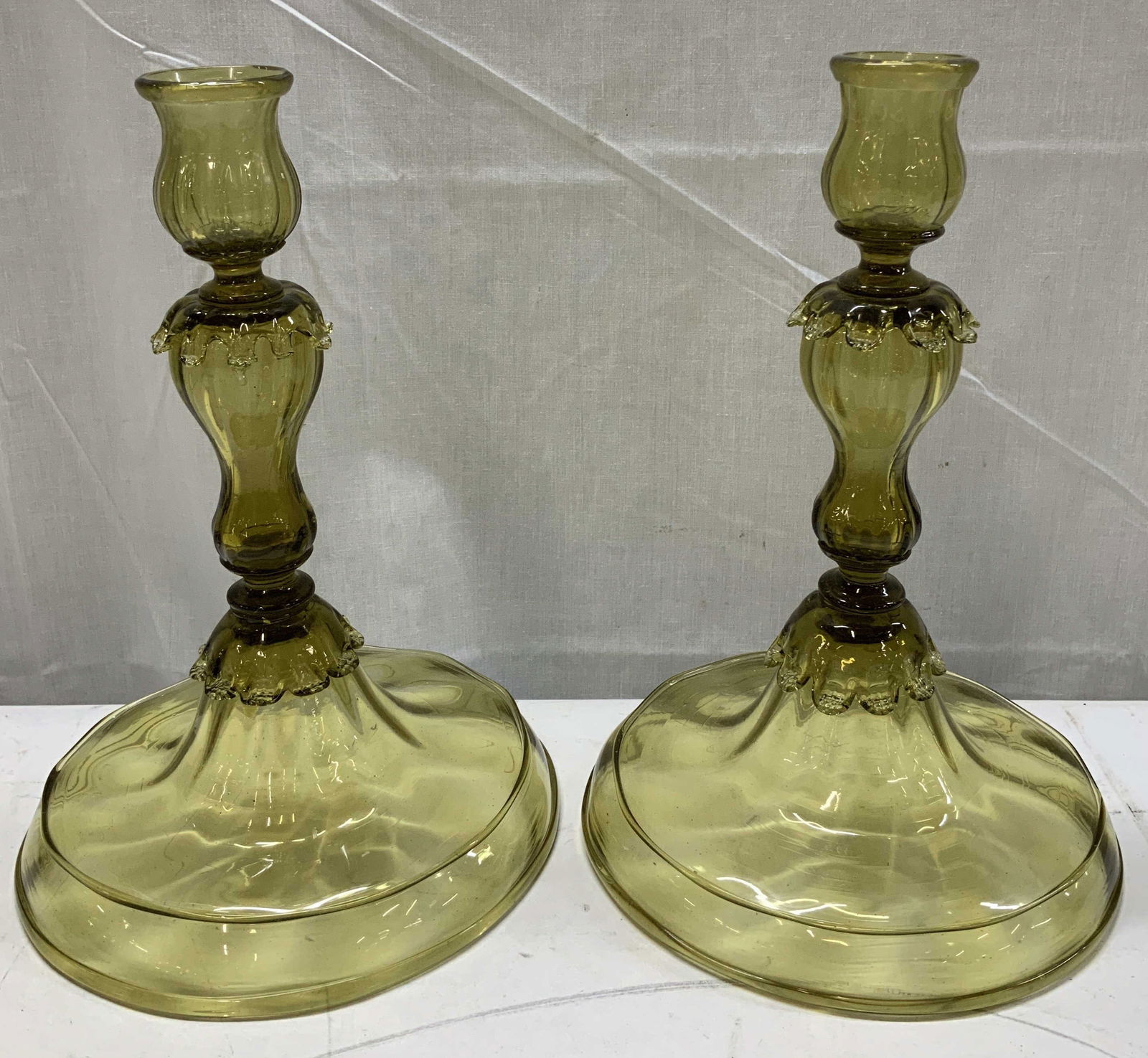 Pair Vtg Glass Candlestick Holders 11.4in: Lot includes, a pair of vintage glass candlestick holders featuring a wide base & petal style stem. Light green/yellow toned. Surface wear consistent to age, use & exposure. Measurements: length
