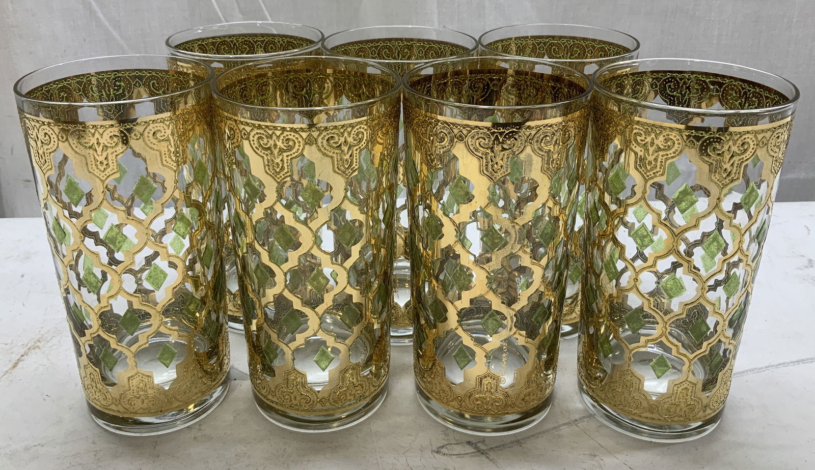 Set 7 Vtg Culver Valencia Gilt Highball Glasses: Lot includes, set 7 of Culver highball glasses featuring an ornate gilt design with green diamond accents. Surface wear consistent to age, use & exposure. Measurements: length 2.7in x width 2.7in x he
