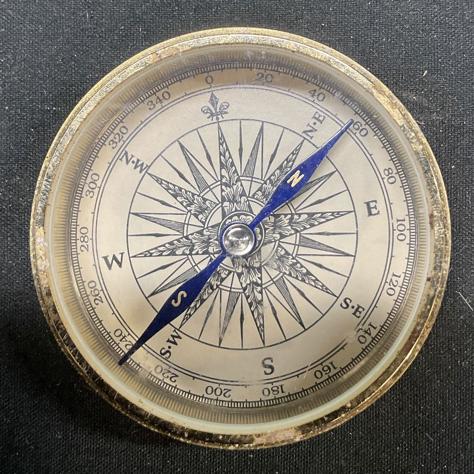 Vintage Brass Toned Metal Pocket Compass: Vintage brass toned metal pocket compass. Circular shape. Face reads numbers and letters. Detailed features. Measures approx 2 inches in diameter. Not tested for function. Wear to surface. Compass, po