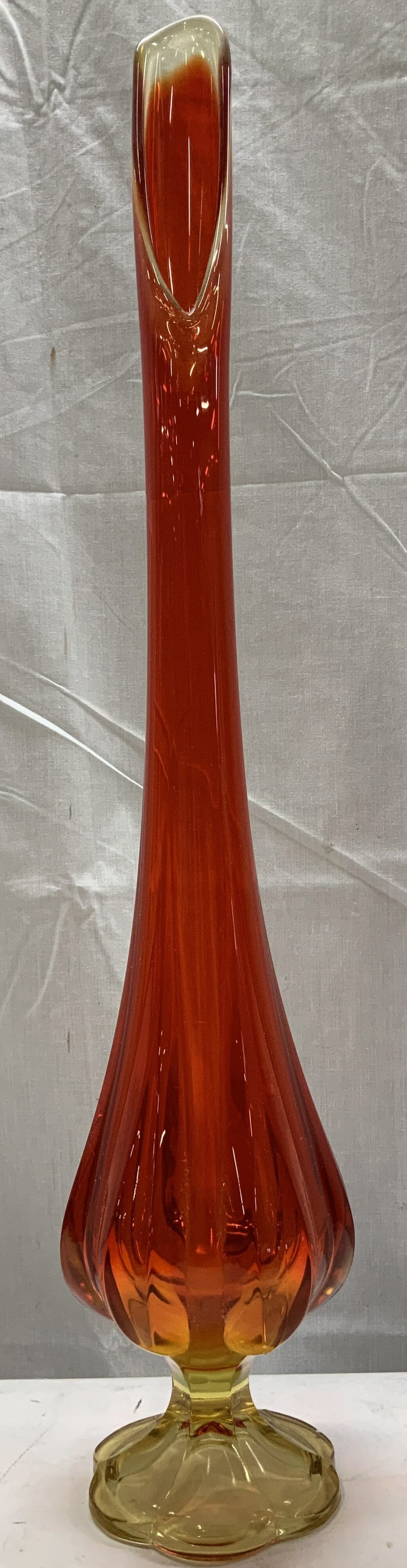 C.1960cs Amberina Swung Glass Vase 22.5in: Circa 1960s Amberina swung vase features a long narrow neck & ribbed style body. 6 petal footed base. Yellow & red toned. Surface wear consistent to age, use & exposure. Measurements: Length 4.2in x w