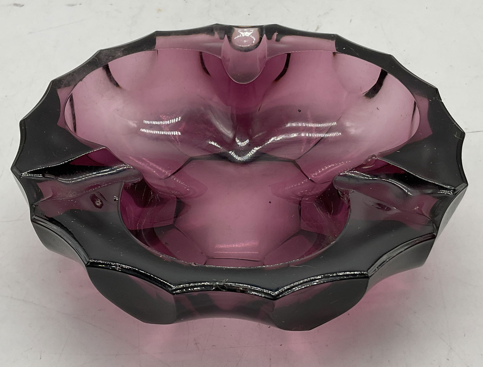 Vintage Murano Style Purple Art Glass Ashtray: Vintage Murano style purple hand blown art glass ashtray. Deep purple color. Scalloped edges. Indentations. Unique shape in center. Faceted design. Measures ht approx 2 inches diam approx 6.5 inches.