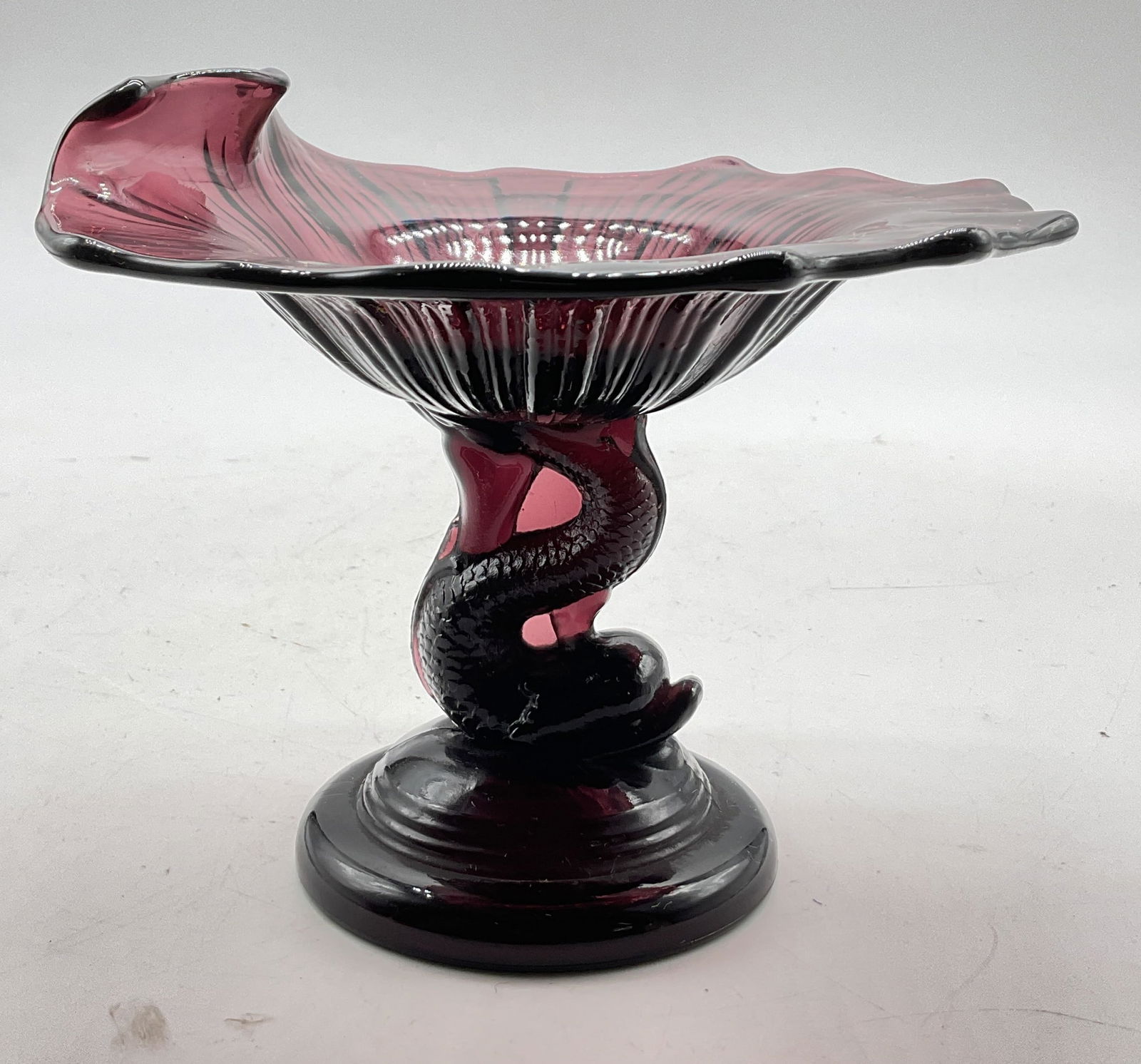 Vintage Purple Art Glass Dolphin Pedestal Tazza: Vintage purple hand blown art glass dolphin pedestal tazza. Round pedestal base. Dolphin figure stem with detailed features and textures. Round wide rim with scalloped edges and curved side. Ribbed te