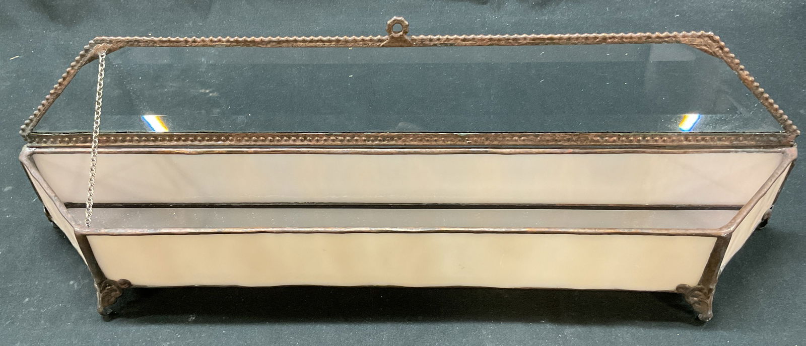 Vintage Glass & Metal Hinged Jewelry Casket: Vintage glass and metal hinged and footed jewelry casket. Rectangular shape with curved edges. Four metal feet on underside, scroll motifs. Geometric pattern on underside. Cream colored glass panels.