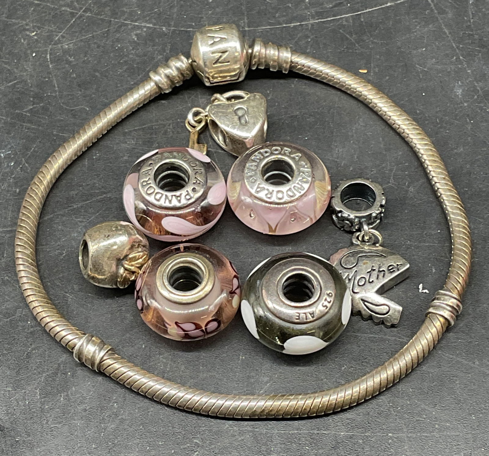Pandora Sterling Silver Bracelet with Charms: Signed Pandora classic sterling silver bracelet with assorted sterling silver charms. Art glass and gold plated charms. Bracelet measures approx. 7 inches long. Marked sterling. Total weight including