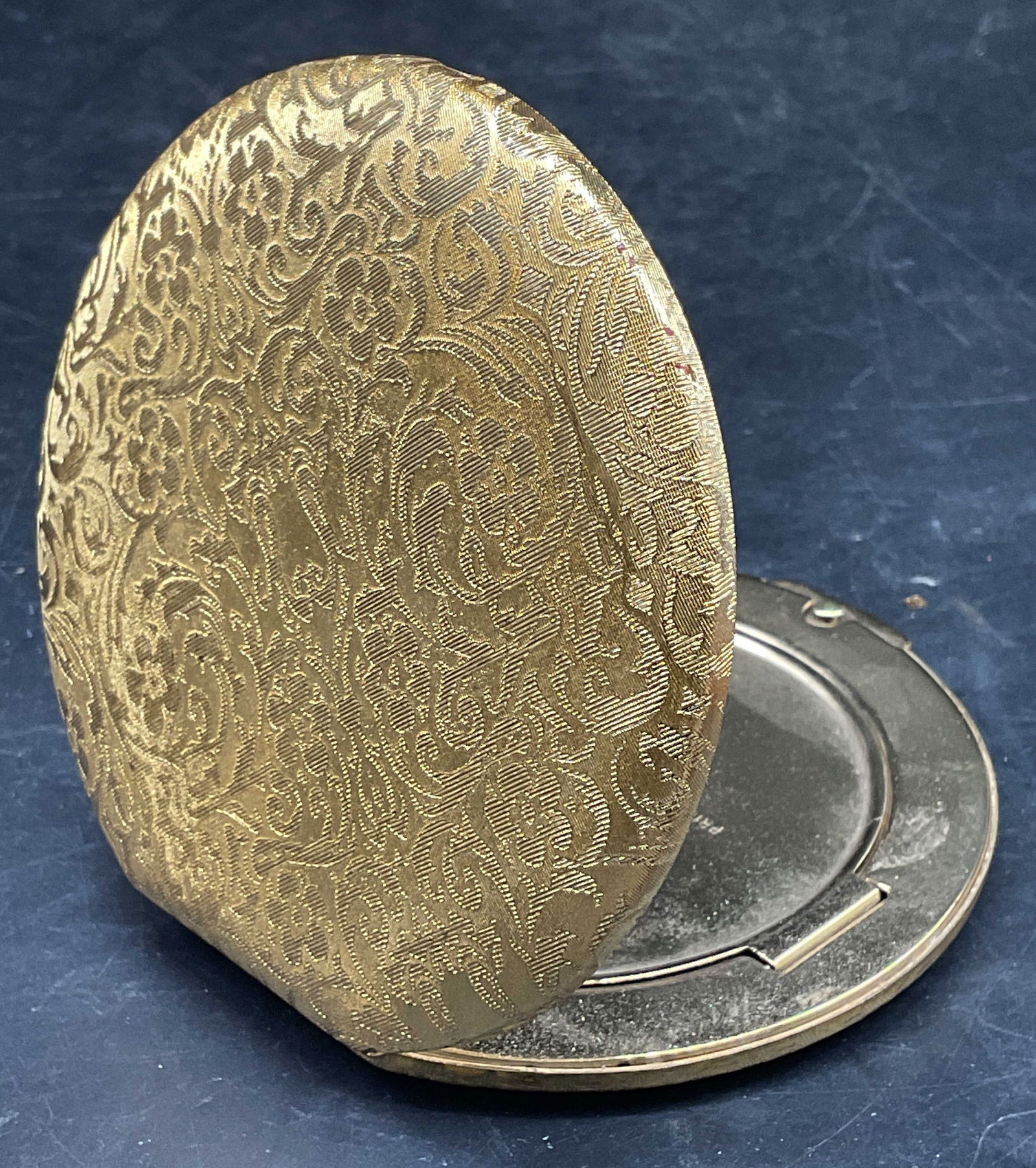 Vtg Princess Marcella Borghese Powder Compact: Vintage signed Princess Marcella Borghese makeup compact with mirror and powder compartment. Ornate floral scroll design. Gold tone metal. Measures approx. 3 3/8 inches wide. Some scratching and