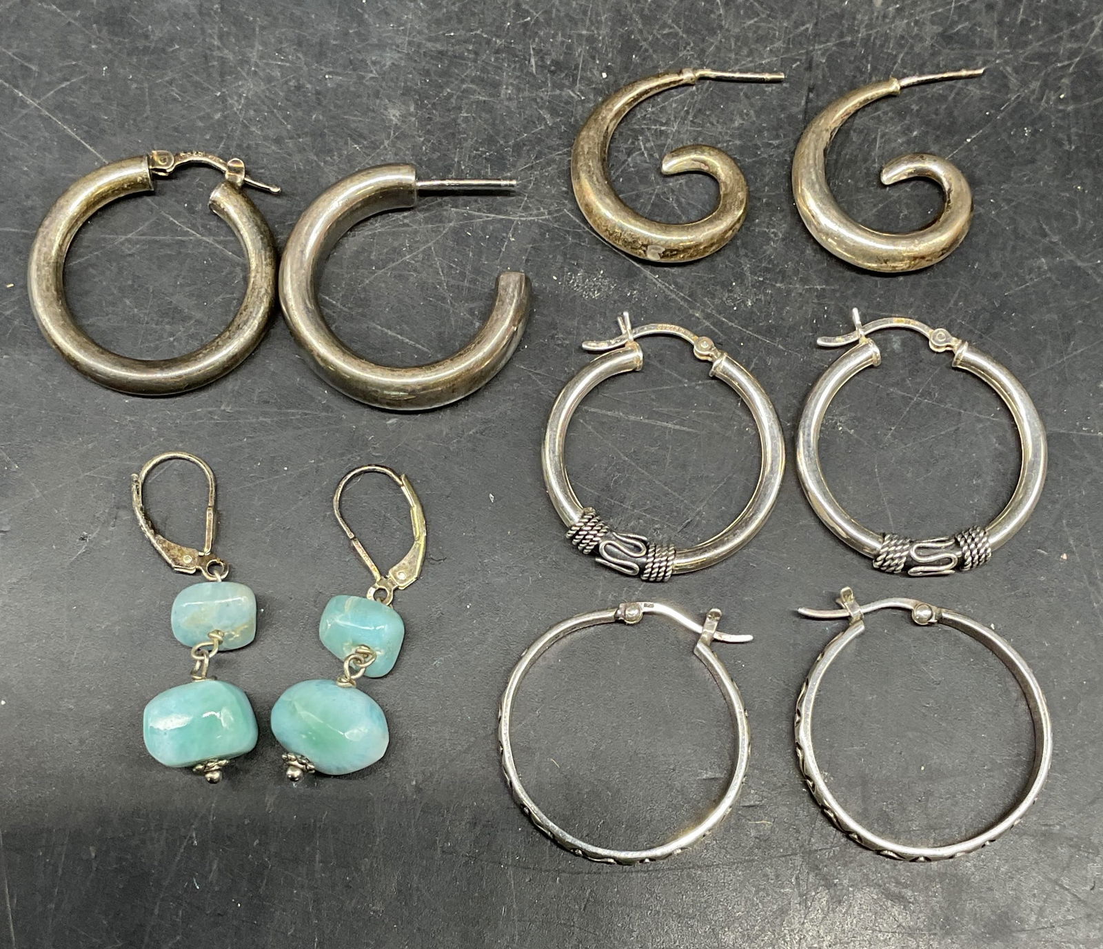Lot 6 Sterling Silver Hoop & Semiprecious Earrings: Lot of 6 jewelry pieces. 2 single hoop earrings. 2 pairs of sterling silver hoop earrings. 1 pair of swirl earrings, 1 pair of sterling silver and blue semiprecious stone earrings. One pair of