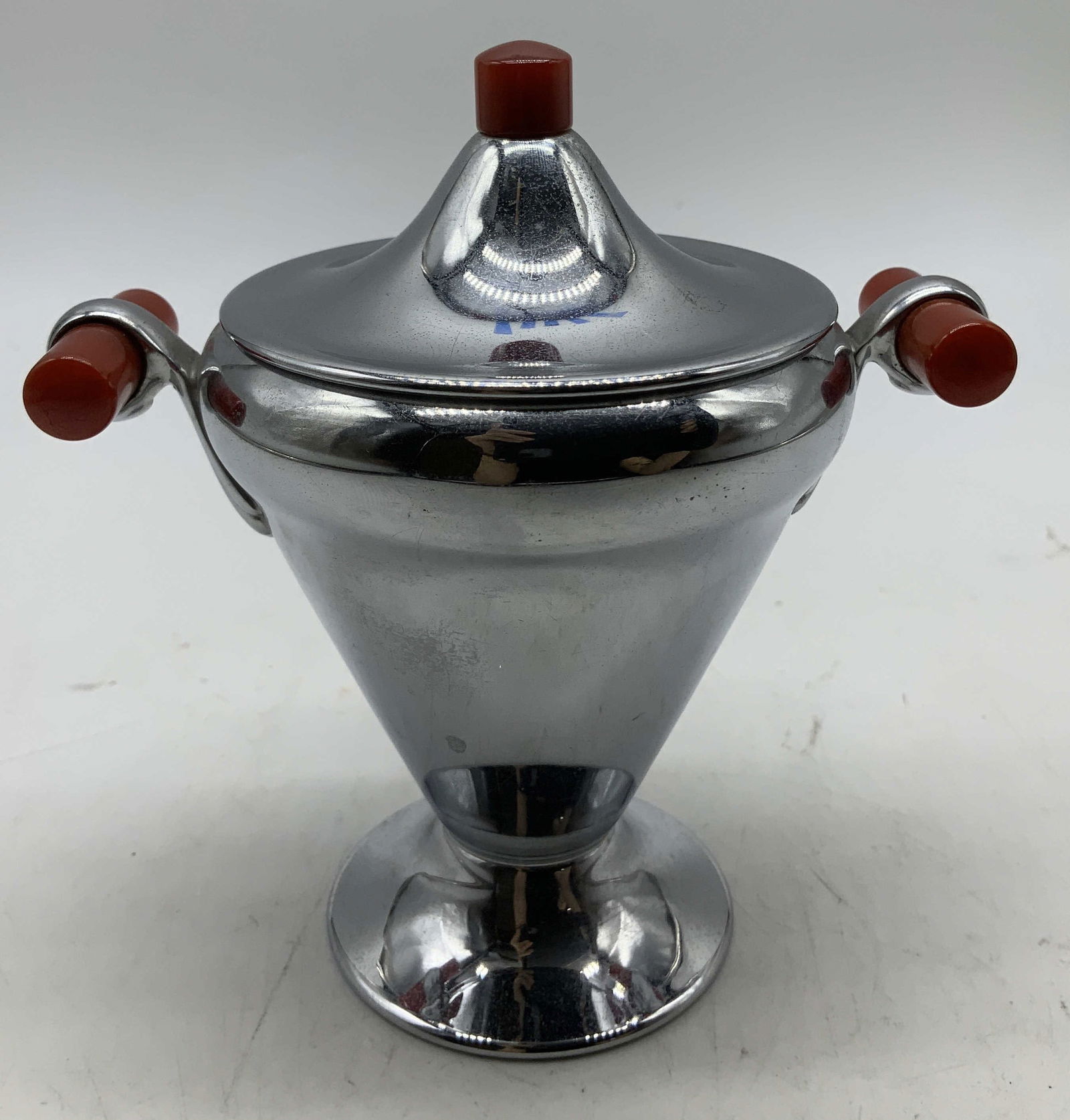 Vtg Manning Bowman Chrome Sugar Bwl USA: Vintage Manning Bowman chrome plated sugar bowl features red Bakelite handles & matching lid finial. Footed base. Signed & marked on underside. Reads, MANNING BOWMAN MERIDEN CONN. MADE IN U.S.A. Surfa
