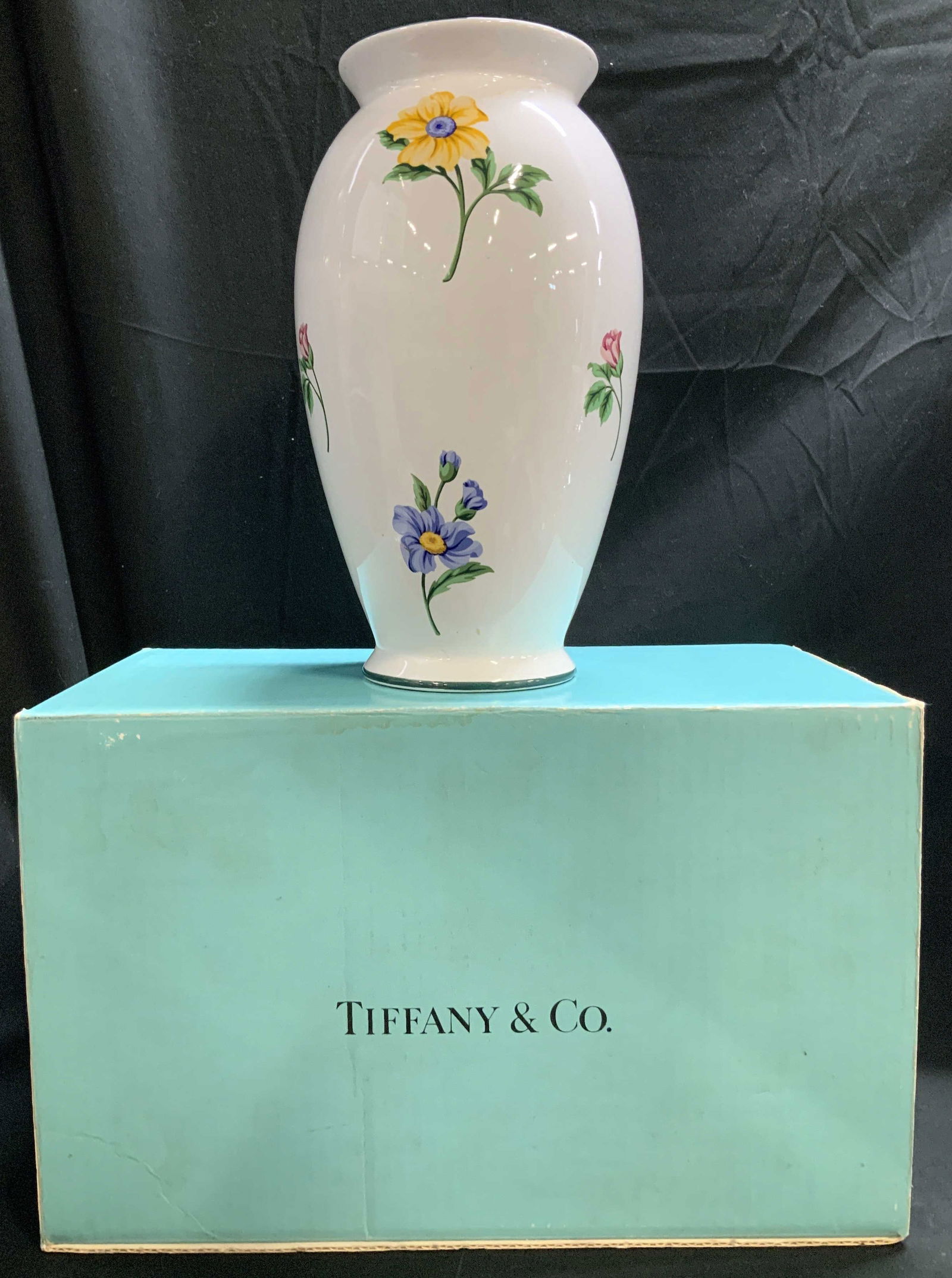 Tiffany & Co. Floral Ceramic Vase W Box: Tiffany & Co. ceramic vase features vibrant floral motifs on body. Green rim on base & top. Comes with Tiffany & Co. box. Surface wear consistent to age, use & exposure. Measurements: length 5.6in x w
