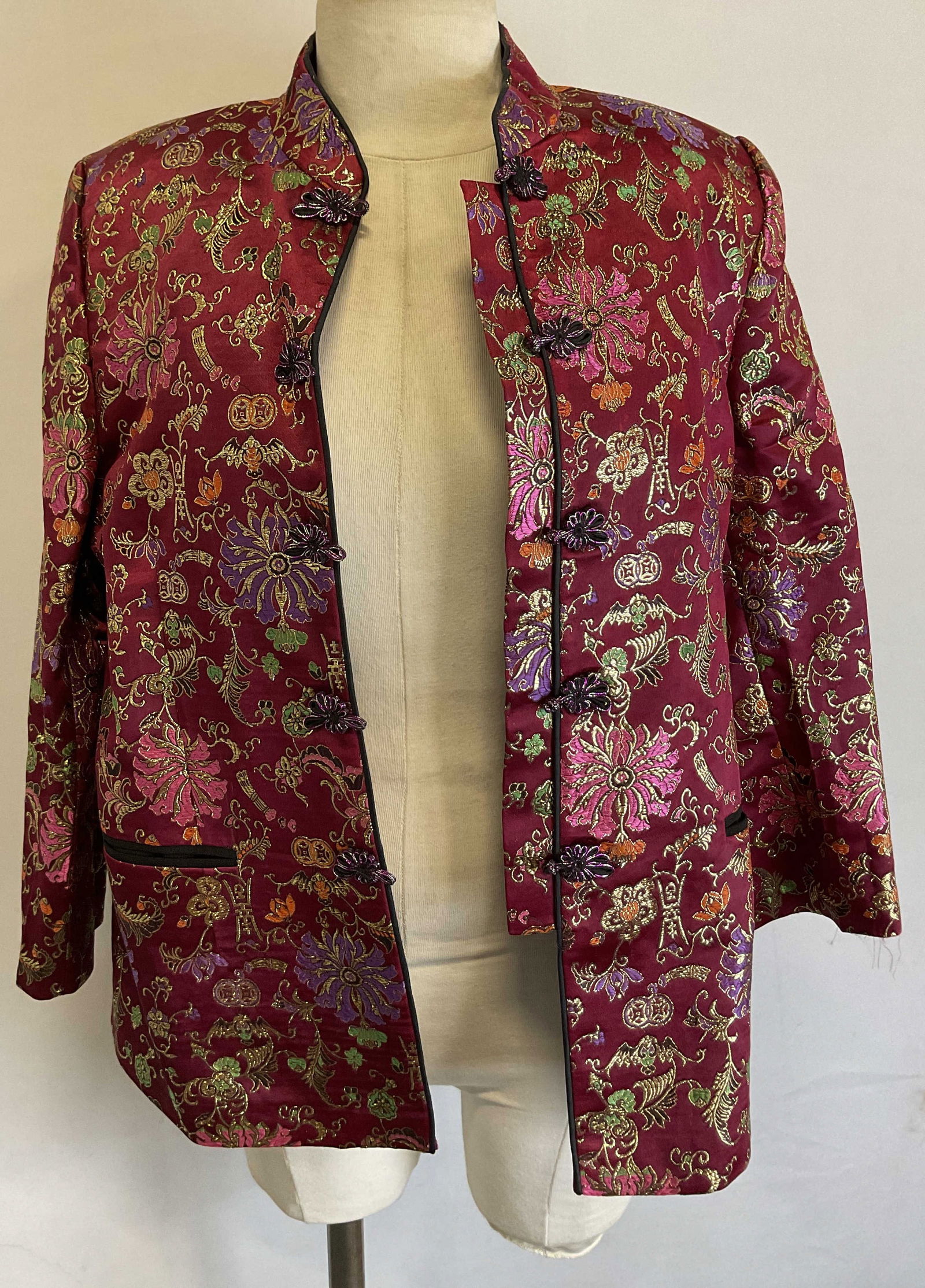 Vtg Red & Gold Toned Floral Brocade Chinese Jacket: Vintage red and gold toned Brocade Chinese jacket. Silk material. Padded shoulders and collared jacket. Embroidered floral motifs and Chinese symbols in varying colors with gilt accents. Decorative tr