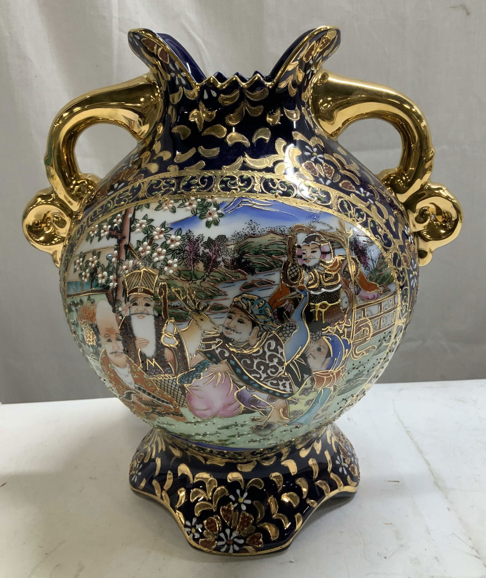 Vtg Hand Painted Satsuma Style Gilt Porc Vase: Vintage Satsuma-style porcelain vase features a cobalt blue background with heavy gilt detailing. Hand painted figural scenes. Vase has a bulbous shape & fluted rim. Gilt handles. No visible signature