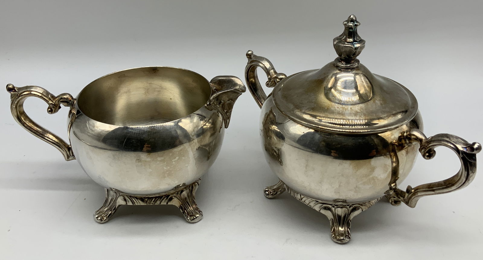 2 Pc International Silver Co. Creamer & Sugar Bwl: 2 piece international silver co. creamer & lidded sugar bowl. Ornate & scroll style handles. Signed & marked on underside. Reads, INTERNATIONAL SILVER COMPANY.MADE IN USA. Surface wear consistent