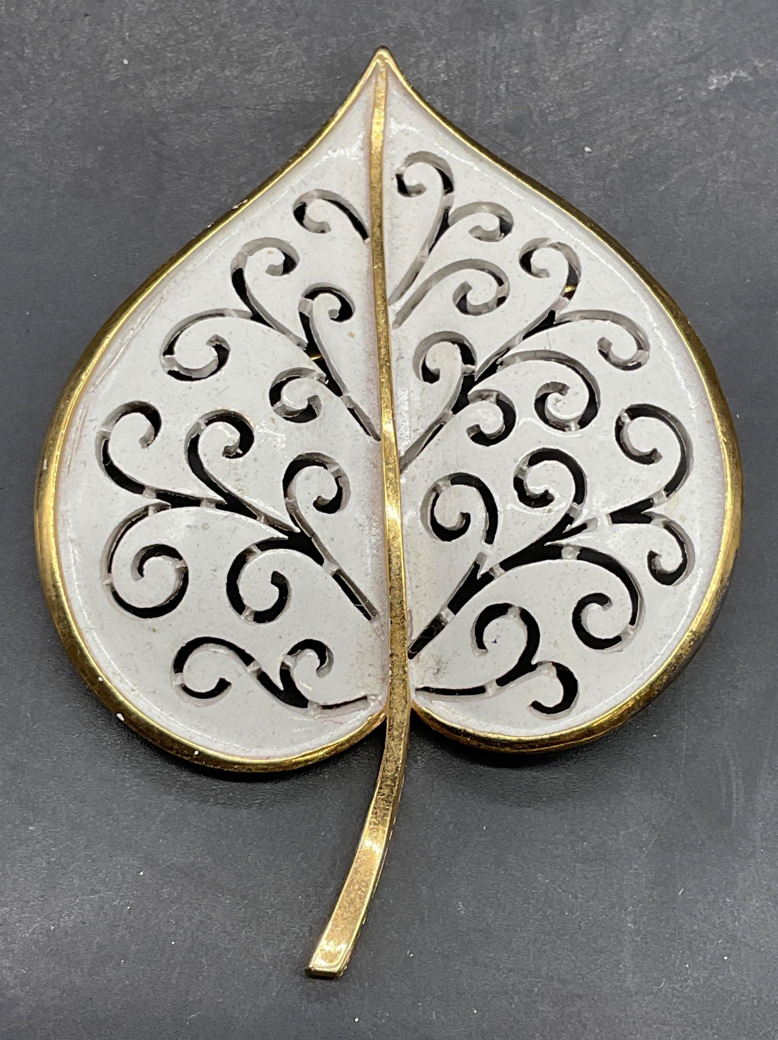 Vtg Trifari Gold Tone Enamel Leaf Brooch: Vintage signed Trifari gold tone white enamel reticulated leaf brooch. Measures approx 2.75 x 2 inches. Some scratching. Jewelry, estate jewelry, costume jewelry, cocktail jewelry, fashion jewelry, ac