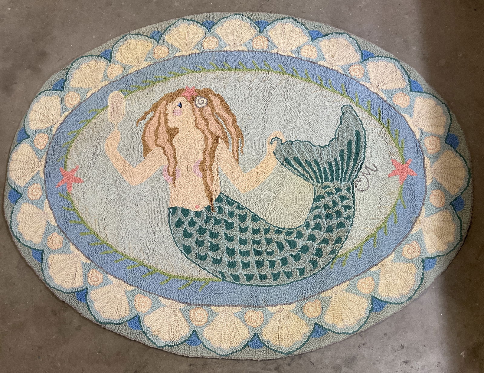 Vtg Claire Murray Mermaid Oval Hooked Wool Rug: Vintage Claire Murray hand woven mermaid oval hooked wool rug. Wool material. Signed CM. Blue shell border. Mermaid motif in center looking into a mirror. Starfish motifs. Colors consist of blue, brow