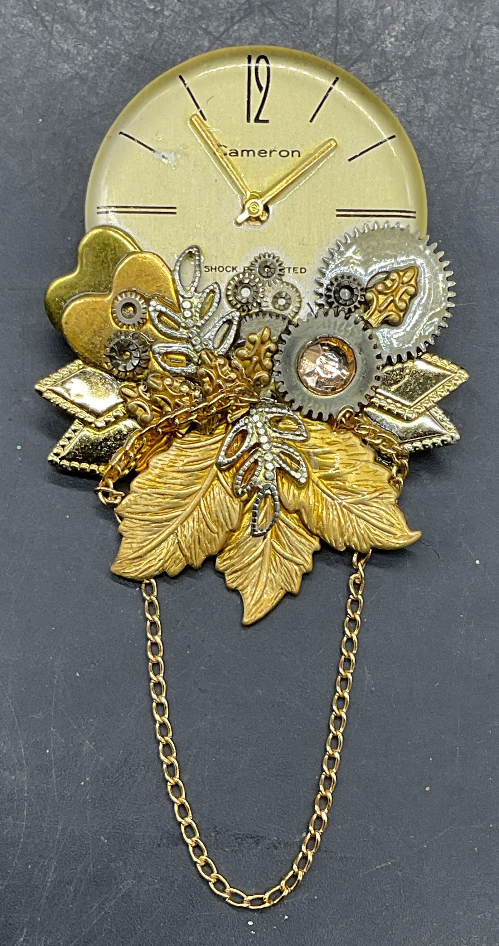 Signed GG Gold Tone Watch Dial Brooch 1999: Signed GG vintage 1999 gold tone brooch with watch dial and leaf and heart motifs. Measures approx 1.75 x 1.5 inches. Some scratching. Jewelry, estate jewelry, costume jewelry, cocktail jewelry, fashi