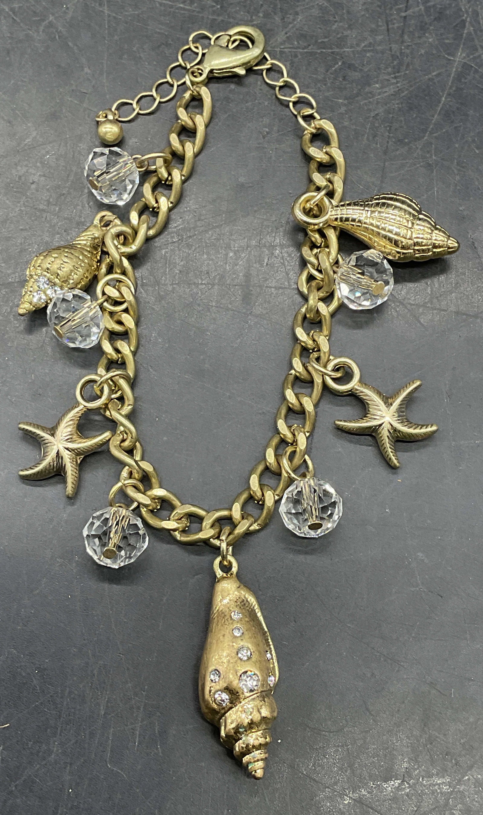 Vintage Gold Tn Crystal Shell Charm Bracelet: Vintage gold tone colorless crystal, shell and starfish motif charm bracelet. Measures approx 9 inches long. Some scratching. Jewelry, estate jewelry, costume jewelry, cocktail jewelry, fashion jewelr