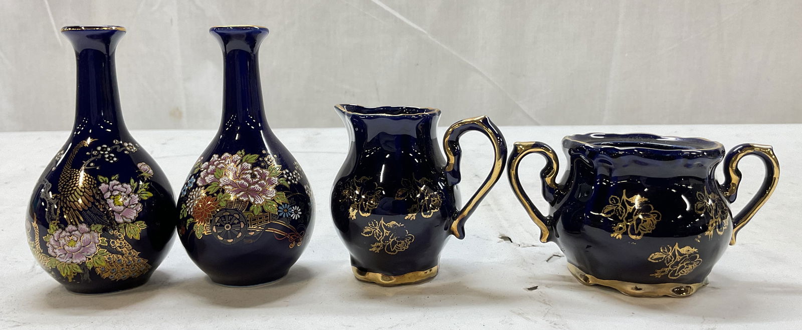 Lot 4 Vintage Cobalt Blue Porcelain Tableware: Lot of 4 items. Vintage Cobalt blue porcelain tableware. Includes two bud vases, one creamer, and one sugar bowl. Creamer and sugar bowl signed Echt Kobalt on underside. Gilt decoration. Scalloped edg