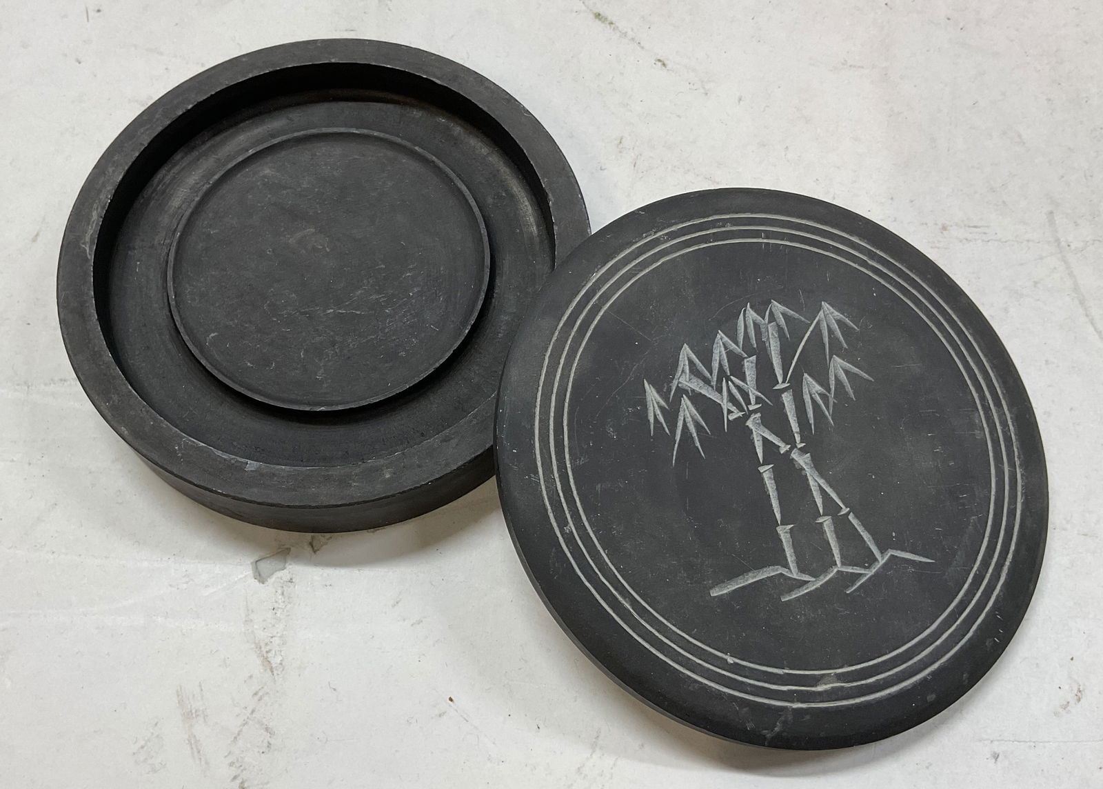 Vintage Chinese Lidded Carved Inkstone: Vintage Chinese lidded carved inkstone. Made of stone. Circular shape. Carved motifs on lid. Inside compartments. Measures approx 4 inches in diameter. Surface wear consistent with exposure. Property