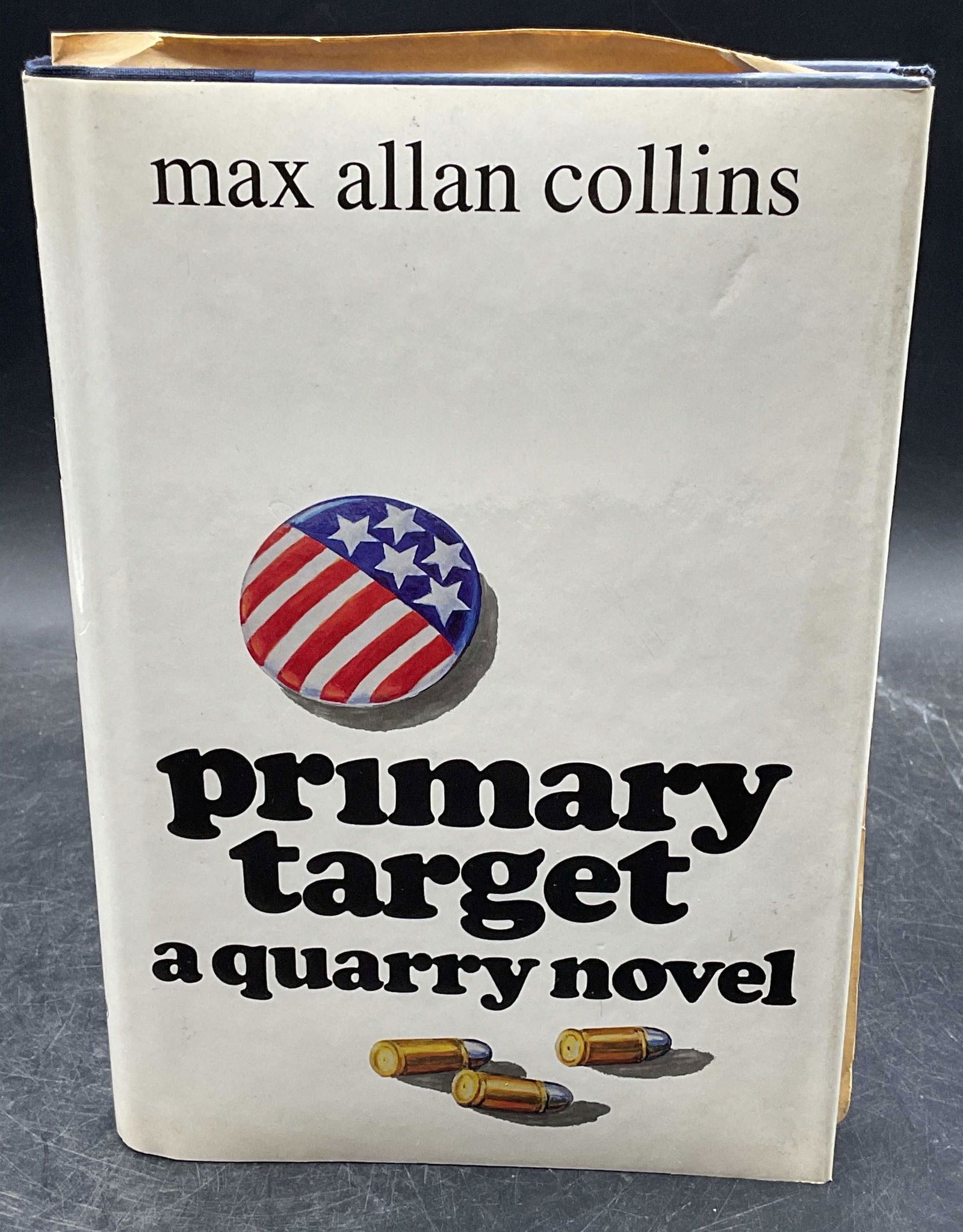 1987 Collins Primary Target Review 1st Edt: Hardcover first edition review copy of Primary Target by Max Allan Collins. Foul Play Press, 1987. Measures approx 8.5 x 5.75 inches. Some wear to cover, pages, and binding consistent with exposure. B
