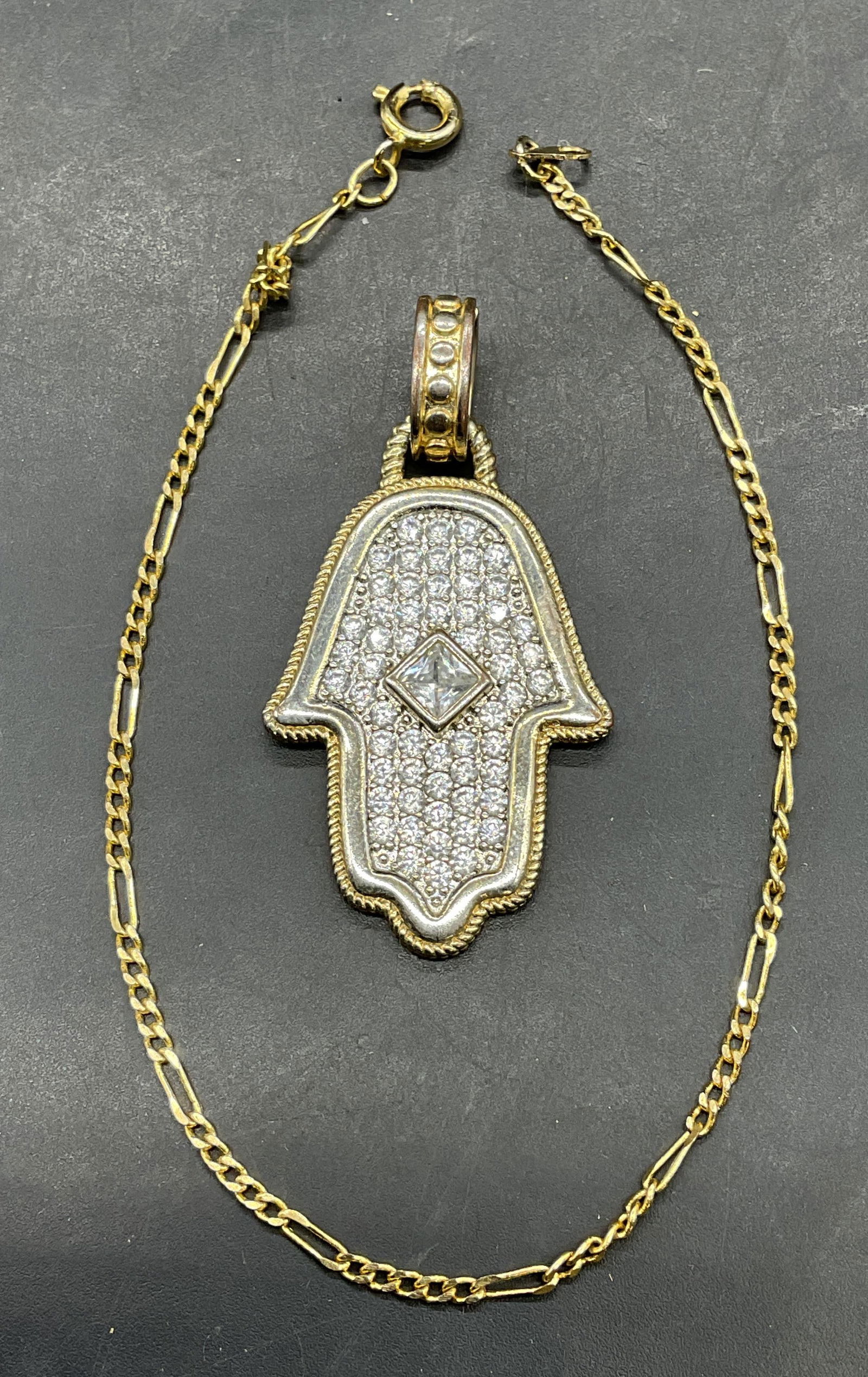 Lot 2 Gold Tone Crystal Hamsa Pendant +: Lot of 2 jewelry pieces. Gold tone Hamsa hand pendant with colorless crystals. Measures approx 1.25 x 1 inches. Gold tone chain bracelet. Measures approx 8 inches long. Chain needs untangling.