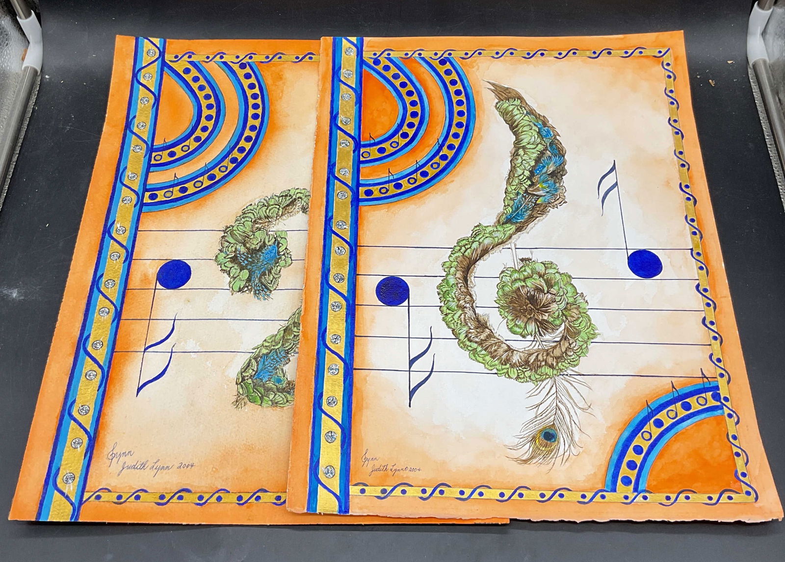 Lot 2 Judith Lynn Music Note Watercolor Paintings: Lot of 2 watercolor paintings on paper. Signed Judith Lynn. Music notes and peacock feathers. Measure approx 12 x 16 inches. Some wear to each consistent with exposure. Property of opera singers estat