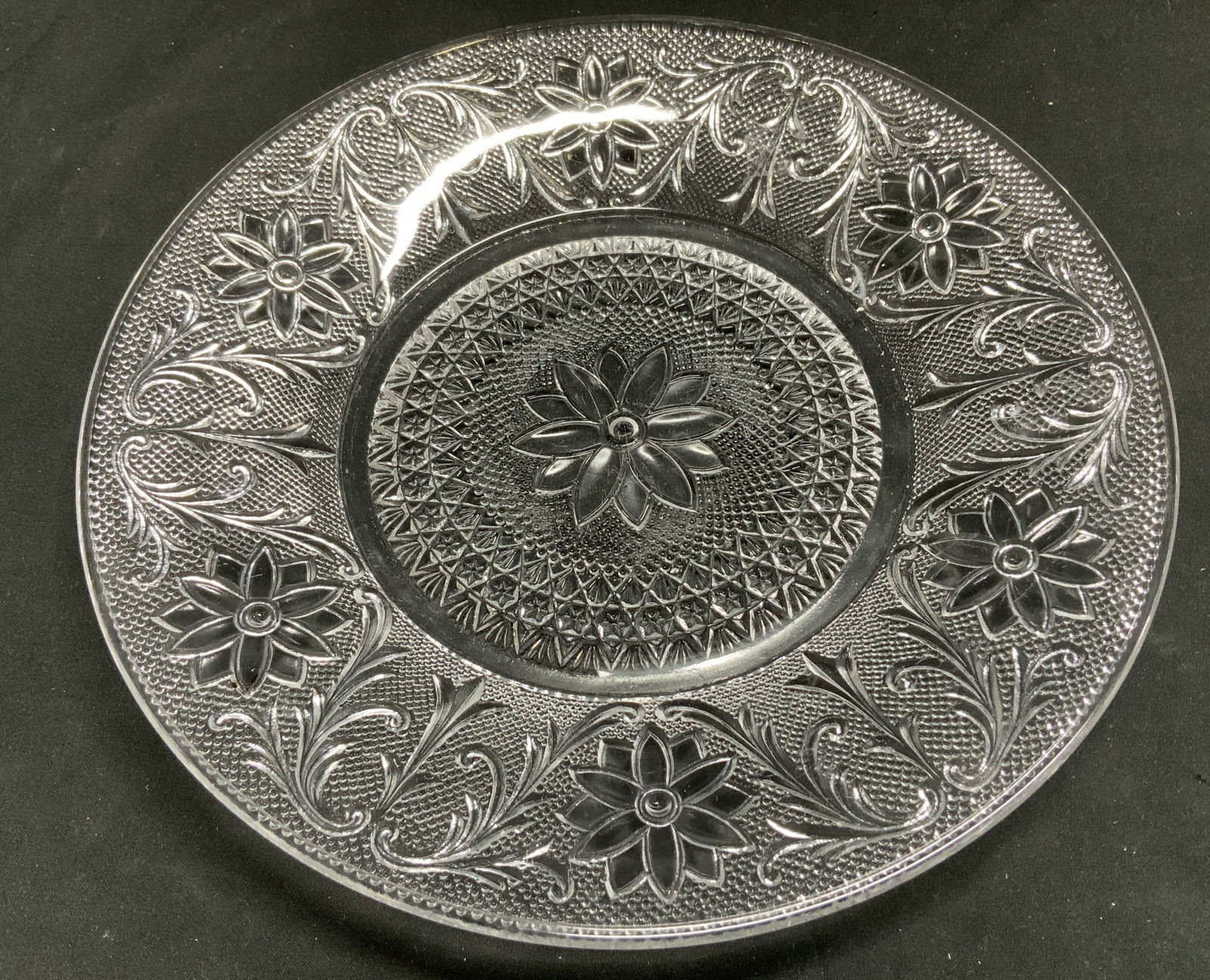 Vtg Clear Glass Floral Motif Dinner Plate: Vintage clear glass dinner plate featuring a pressed glass design with floral & geometric motifs. Surface wear consistent to age, use & exposure. Measurements: length 10.3in x width 10.3in.
