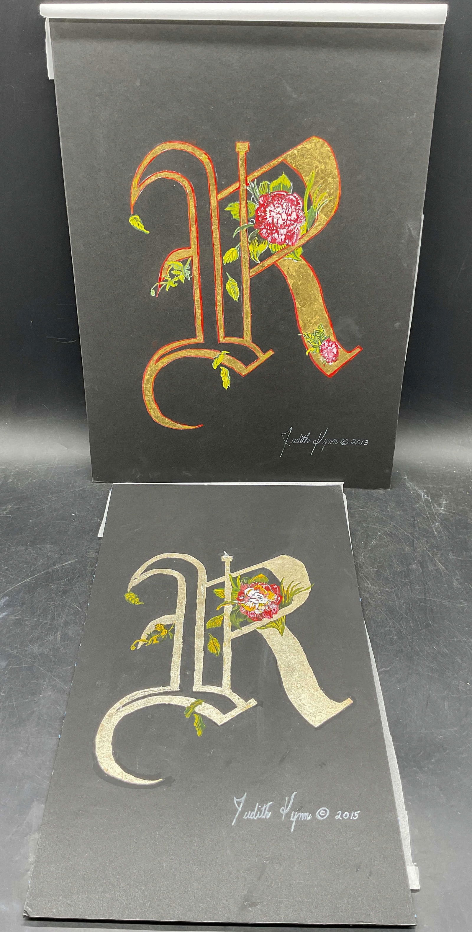 2 Judith Lynn Gothic Letter R Gilt Watercolors: Lot of 2 watercolor, ink, and gold leaf paintings on board. Signed Judith Lynn. Gothic Letter R. Larger measures approx. 15 x 11inches. Some wear consistent with exposure. Some residue and