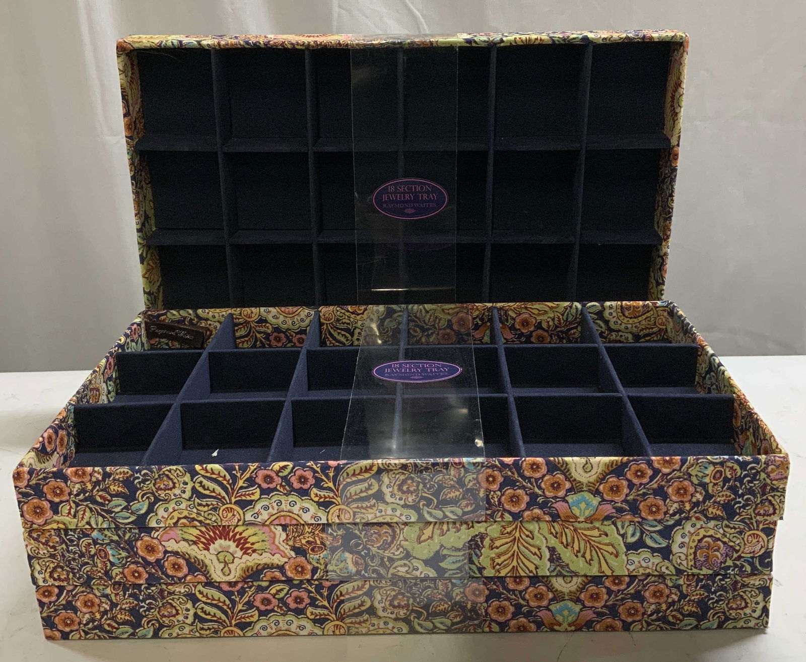 Set 4 Raymond Waites 18 Section Jewelry Tray: Lot includes, 4 Raymond Waites 18 section jewelry tray featuring a decorative patterned exterior & blue velvet-lined interior. Surface wear consistent to age, use & exposure. Measurements: length