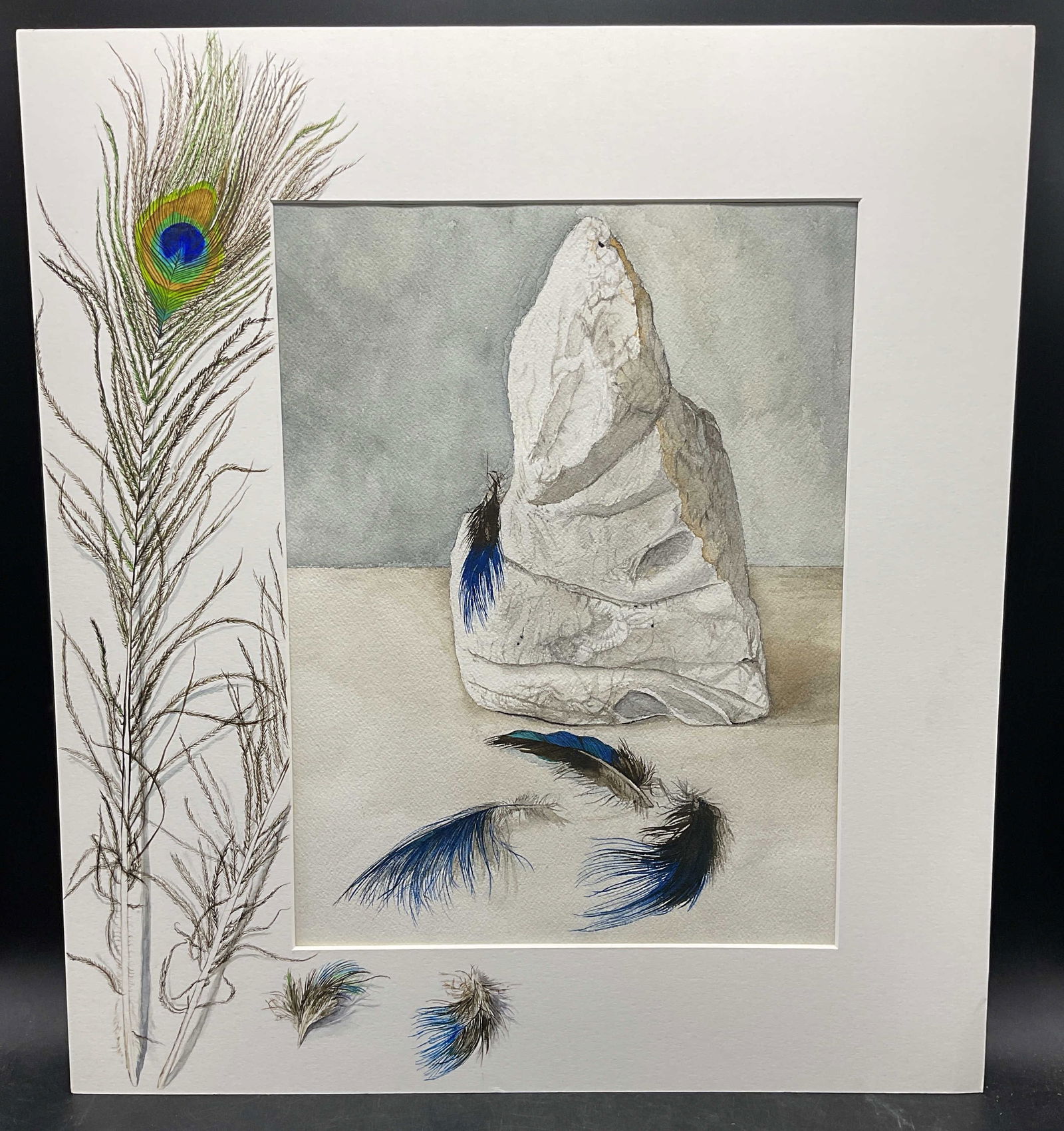 Judith Lynn Blue Feathers Watercolor Painting: Matted watercolor painting on paper. Signed Judith Lynn. Blue feathers and rock with peacock feather painted on mat board. Total dimensions approx. 20 x 18 inches. Some wear consistent with exposure.