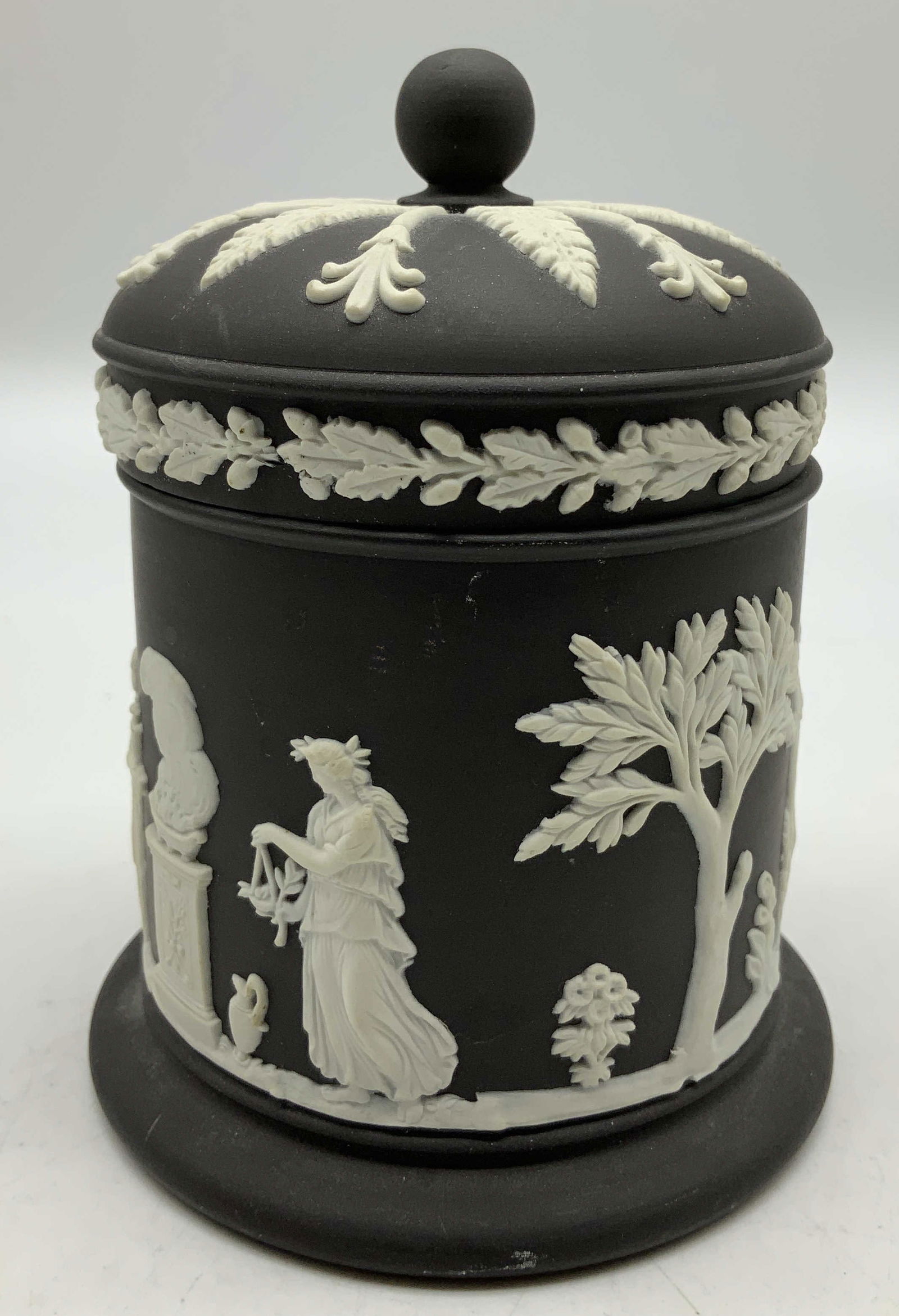Wedgwood Jasperware Tobacco Jar ENGLAND: Wedgwood Jasperware lidded tobacco jar featuring white relief classical figures. Intricate detailing. Signed & marked on underside. Reads, WEDGEWOOD MADE IN ENGLAND. Surface wear consistent to age, us