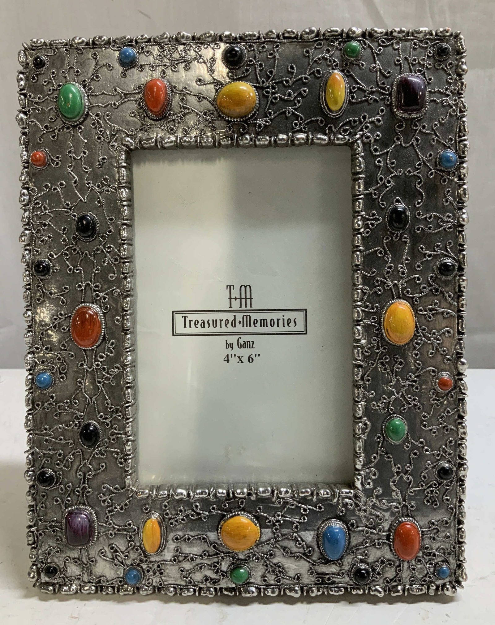 Treasured Memories By Ganz Ornate Frame: Treasured Memories by Ganz photo frame, featuring an ornate silver-toned frame decorated with colorful stones. Surface wear consistent to age, use & exposure. Measurements: 4x6in. Treasured memories b