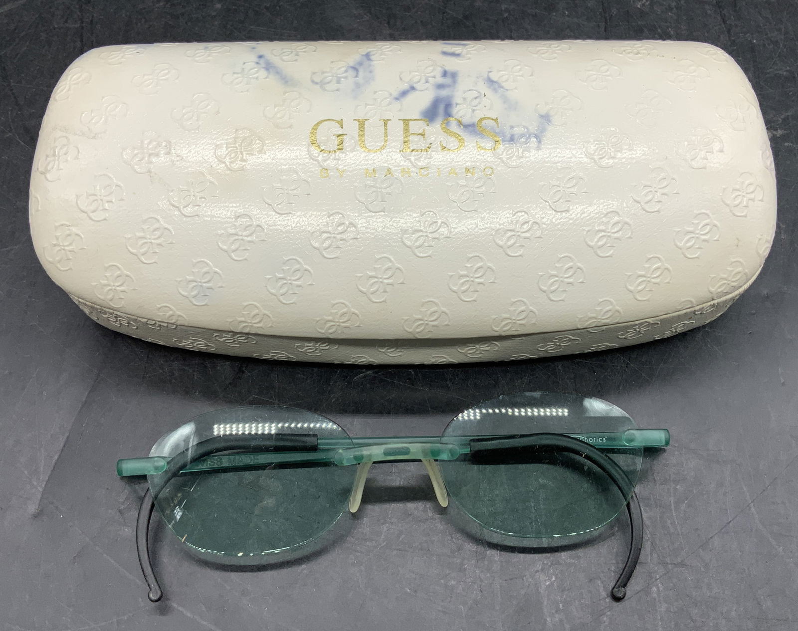 Lot2 Guess White Hard Case & EyePhorics Eyeglasses: Lot includes, GUESS by Marciano white sunglasses hard case & EyePhorics (Swiss Made) green rimless eyeglasses. Surface wear consistent to age, use & exposure. Interior of hard case needs reattachment.