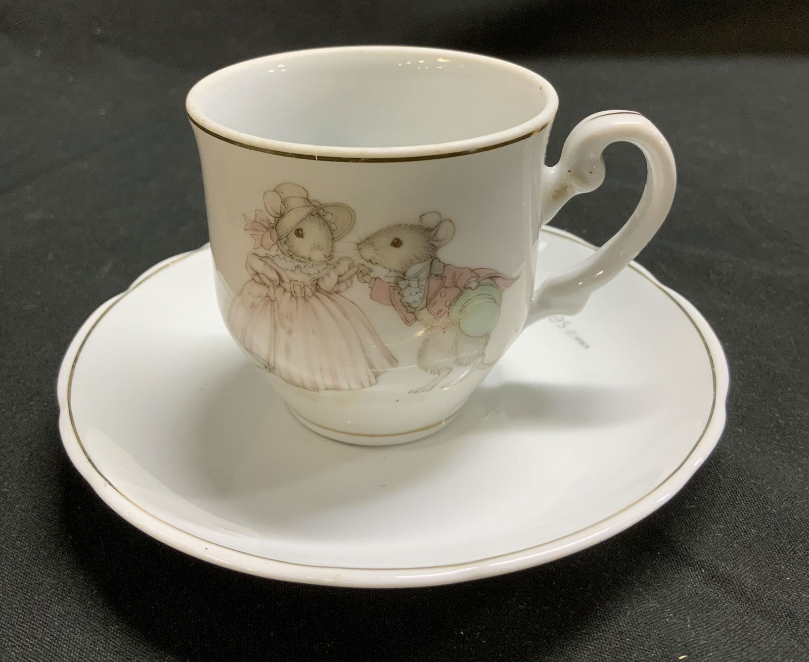 1976 Tiny Talk Porc Teacup & Saucer BRAZIL: Lot includes, 1976 Tiny Talk genuine porcelain teacup & saucer. Silver rim. Saucer reads, Good times make happy memories. Signed & marked on underside. Reads, TINY TALK GENUINE PORCELAIN. MADE IN BRAZ