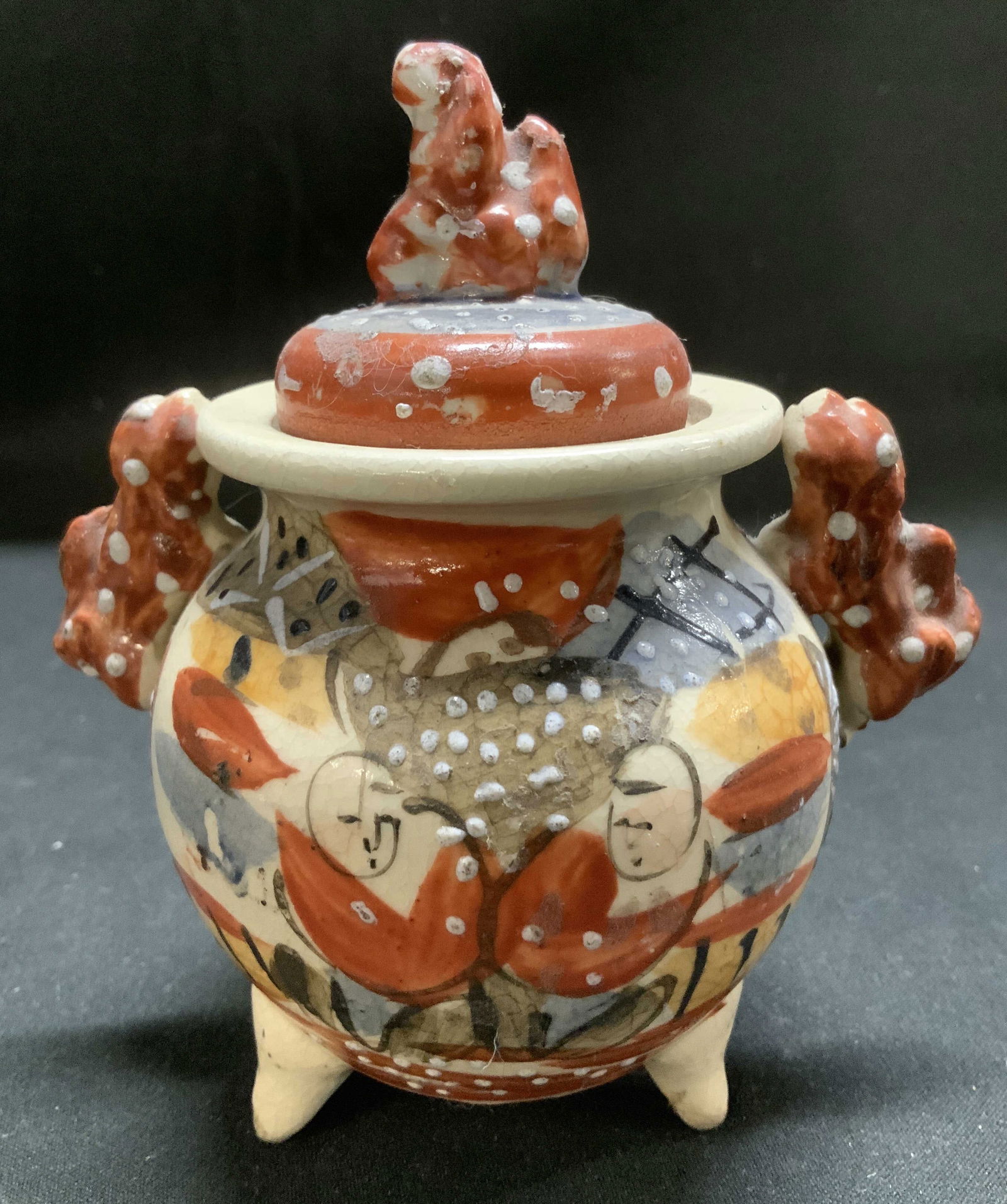 Vtg Hand Painted Satsuma Style Lidded Vessel: Vintage satsuma style lidded vessel features hand painted accents & red finial. Stylized handles. Ceramic material. Surface wear consistent to age, use & exposure. Measurements: length 4in x width 2.7