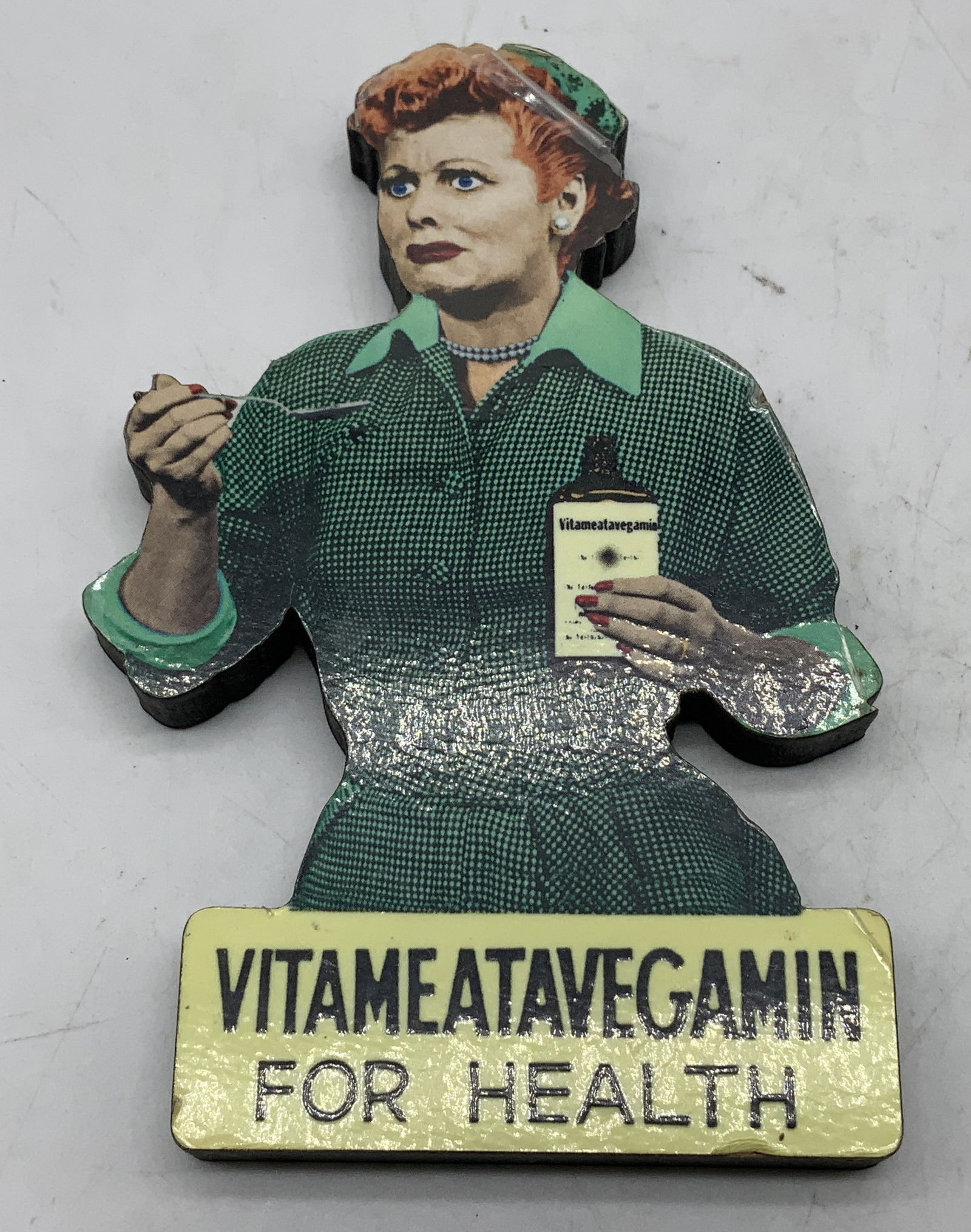 I Love Lucy Vitameatavegamin Wood Magnet CANADA: Wood magnet featuring Lucille Ball from the iconic I Love Lucy Vitameatavegamin commercial. Signed & marked on underside. Reads, I LOVE LUCY. DESILU, TOO, LC. MADE IN CANADA. Surface wear consistent t