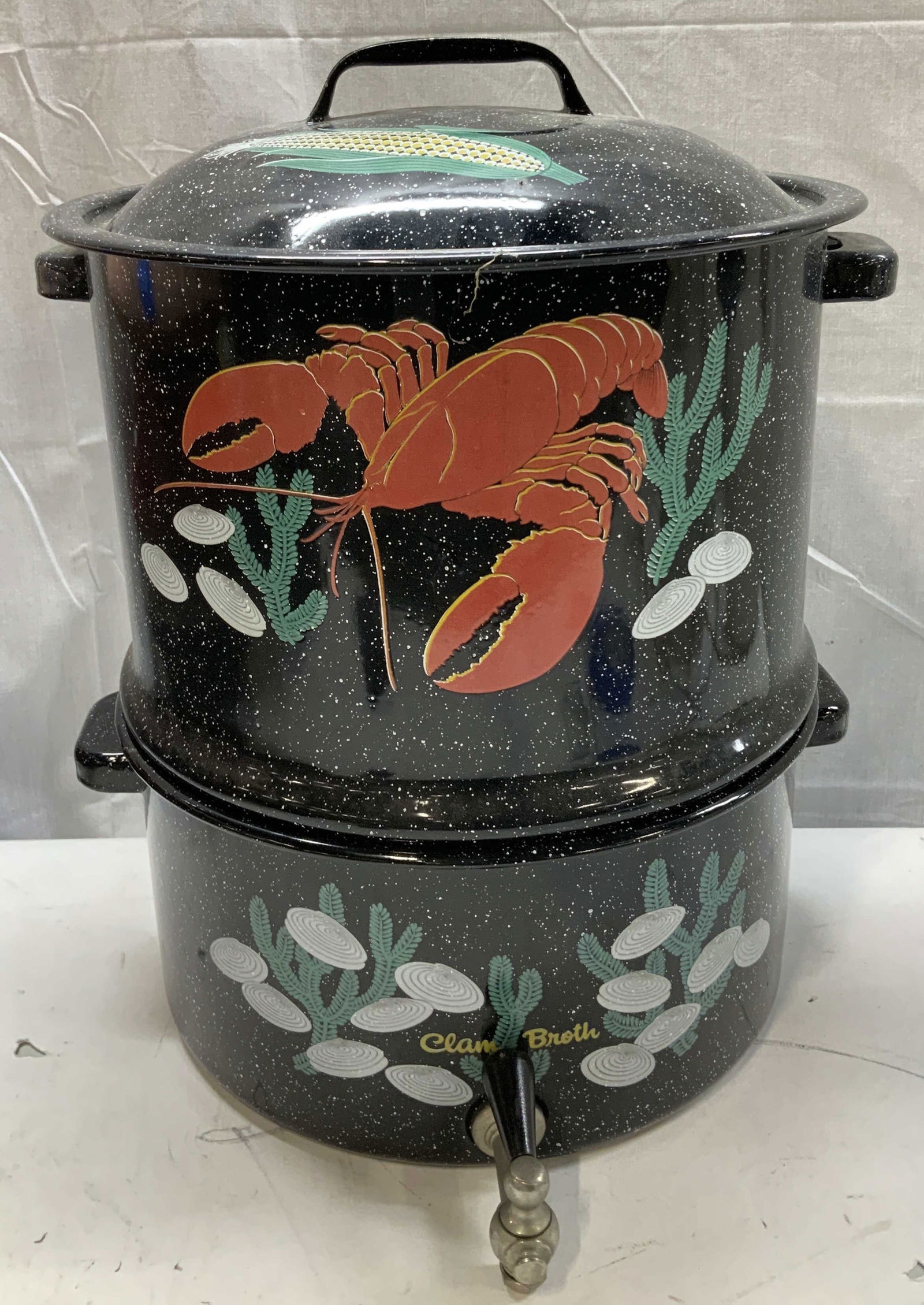 Black Speckled Enameled Clam & Lobster Pot: Black speckled enamelware clam & lobster steamer pot. Features graphics of a lobster, clams & corn. Spigot for draining & two piece design. Surface wear consistent to age, use & exposure. Measurements