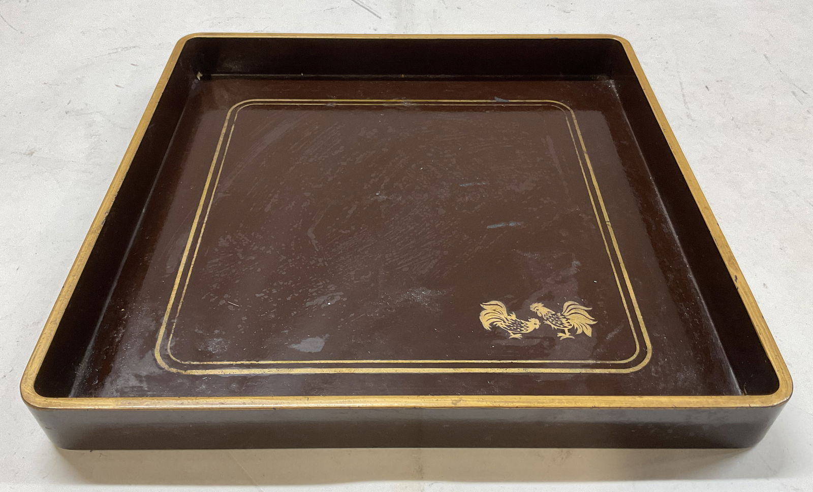 Gallo Brown Lacquer Rooster Serving Tray: Gallo brown lacquer rooster serving tray. Reads Gallo on underside. Square shape. Gilt decorated rim. Gold toned hand painted rooster motifs. Measures approx 11 x 11 x 1.5 inches. Scratching observed.