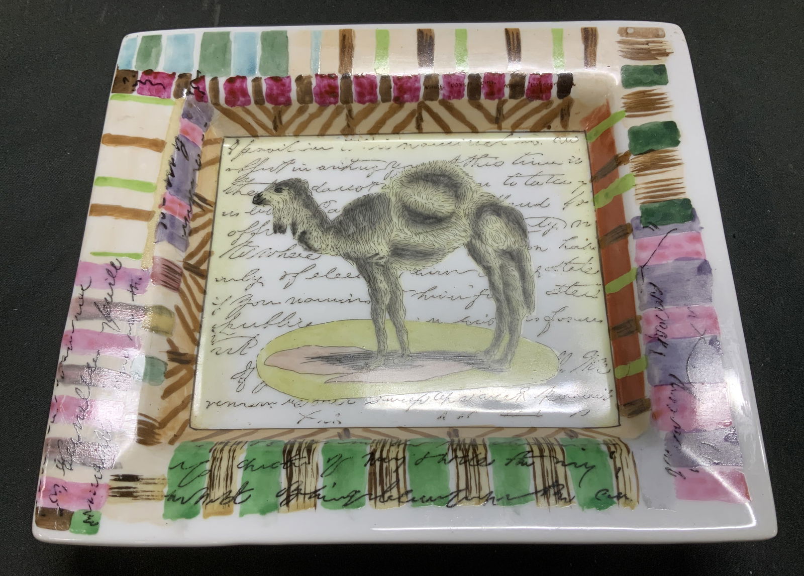 John Derian Camel Porcelain Deco Dish: John Derian Tozai Home porcelain decorative dish features an illustration of a camel & text in center. Striped rim. Signed & marked on underside. Reads, JOHN DERIAN TOZAI HOME. Surface wear consistent