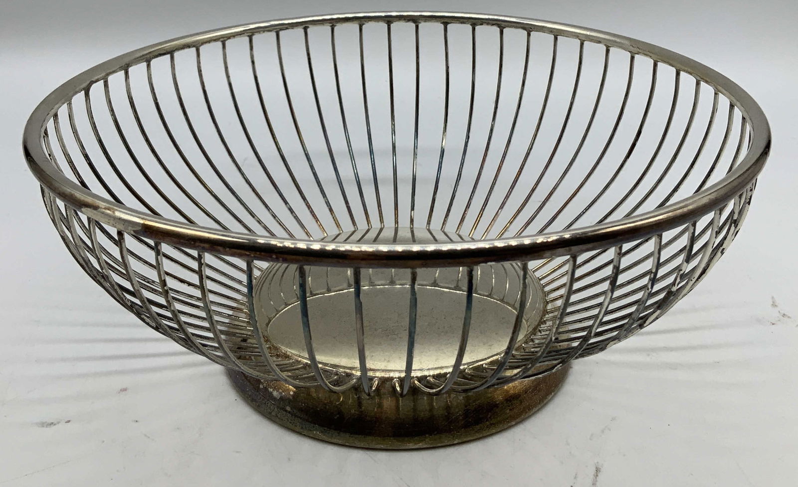 Vtg Silver Plated Footed Wire Basket ITALY: Vintage silver plated basket features an open wire design & round base. Signed & marked on underside. Reads, MADE IN ITALY. Surface wear consistent to age, use & exposure. Measurements: length 8in x w