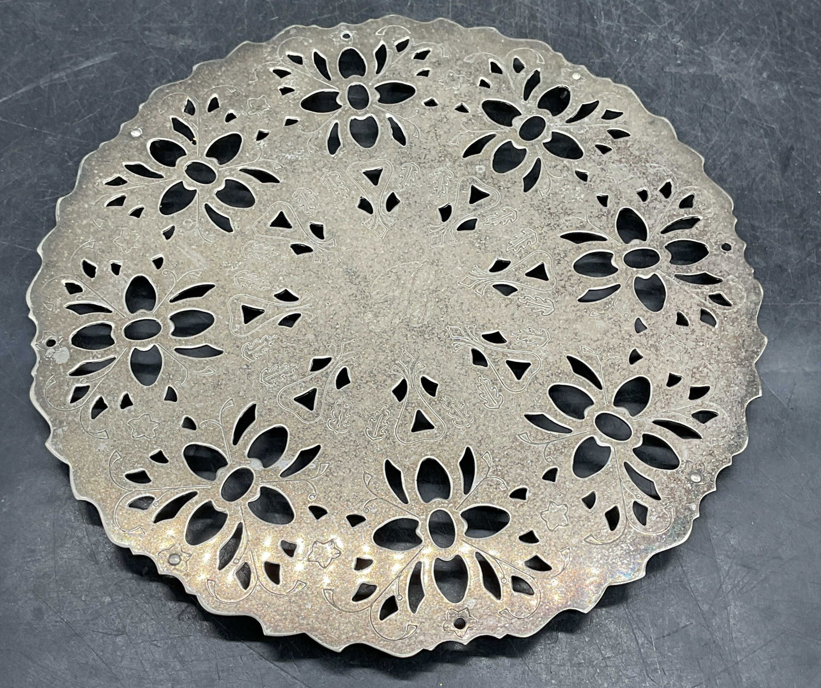 Vintage Raimond Silver Plated Trivet: Vintage signed Raimond silver plated trivet. Reticulated floral design with scalloped rim. Ball footed base. Engraved monogram B at center. Measures approx. 7.5 inches wide. Wear including