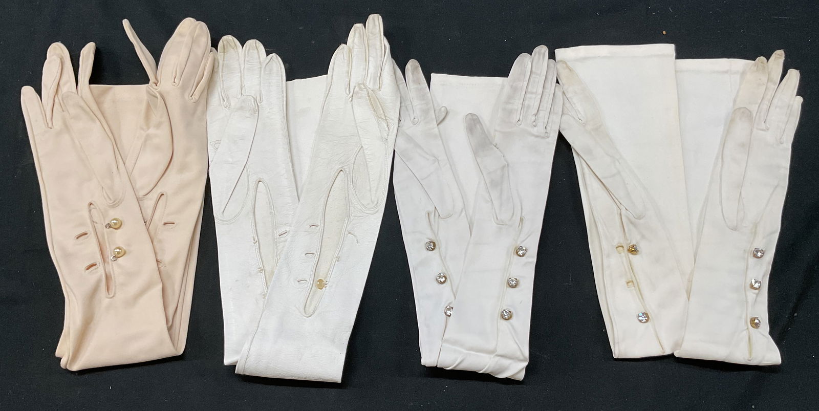 Lot 4 Vintage White Opera Length Gloves Germany: Lot of 4 pairs of gloves. Two marked made in Germany. Shades of white vary. Leather and silk material. Decorative buttons. Largest measures approx 4 x 22 inches. Blemishes and losses observed. Propert