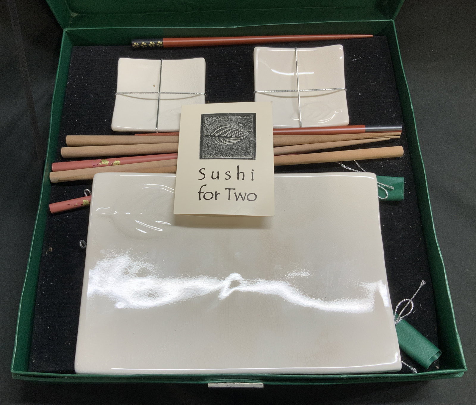 Set12 Exclusively Discovery Sushi for Two Set: Lot includes, 1 green box with silver toned leaf emblem, 1 ceramic serving dish with embossed leaf motif, 2 square dipping dishes & 8 chopsticks. Sushi for Two. Signed & marked. Reads, Exclusively for