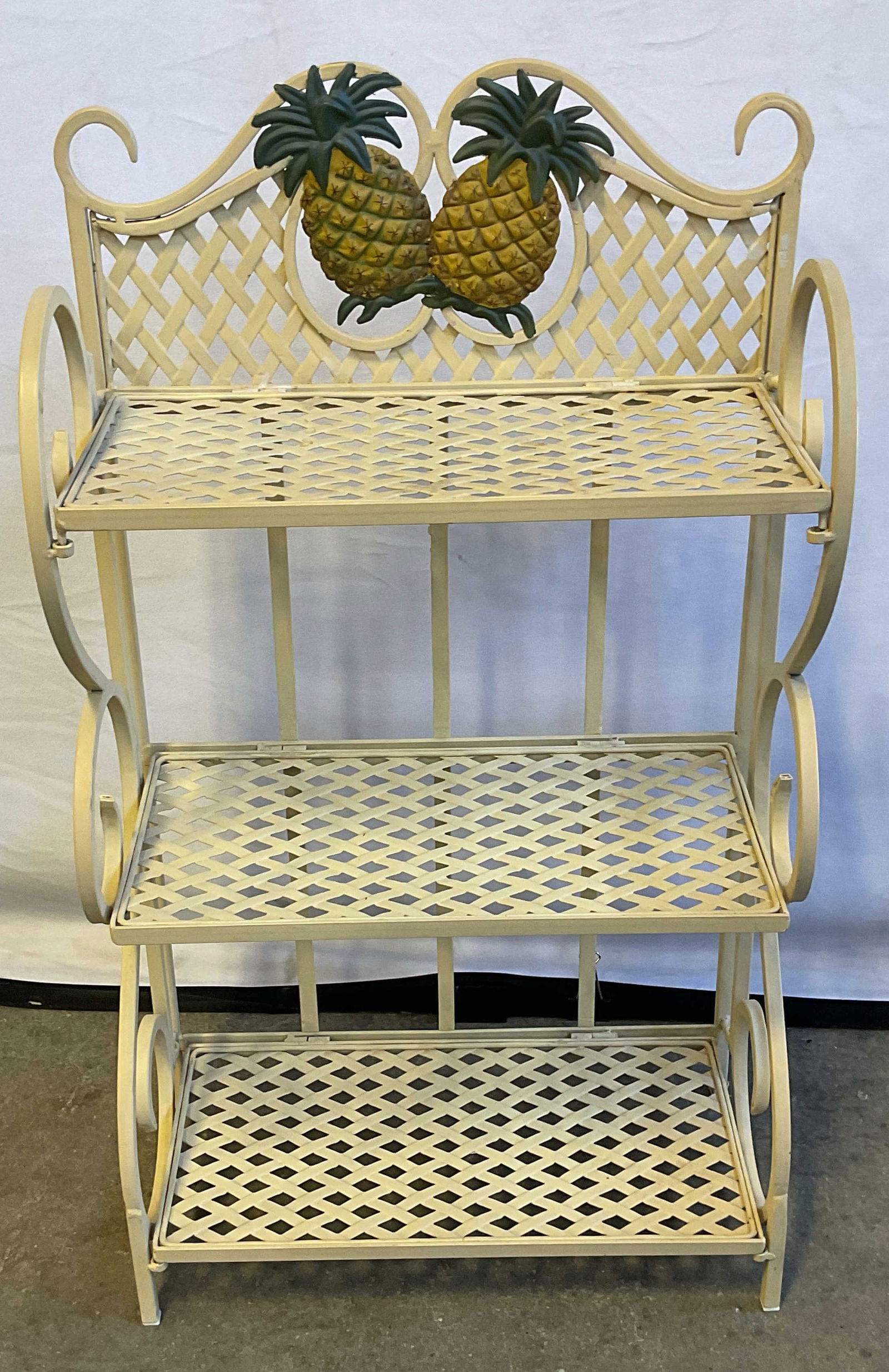 White Enamel Pineapple 3 Tier Plant Stand: White cream enameled metal 3 tier plant stand with hinged shelves and pineapple motif. Measures approx. 15.5 x 8 x 27.75 inches. Some scratching and loss to enamel. Plant stand, metal plant stand,