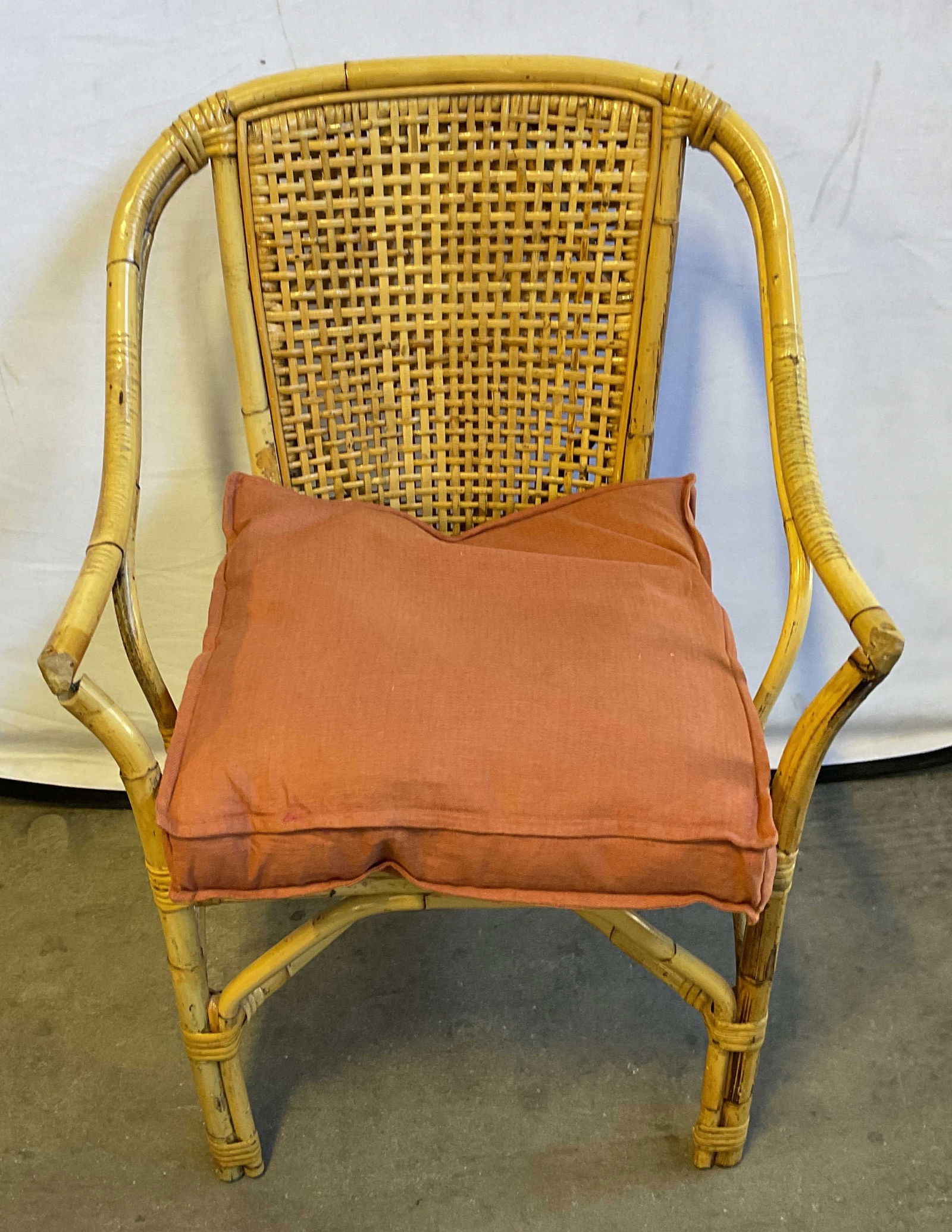 Vintage Bamboo Rattan Cane Armchair: Vintage bamboo frame armchair with woven rattan caning. Includes red seat cushion. Measures approx. 23.5 x 17 x 34 inches. wear including scratching and some losses. Arms slightly loose from