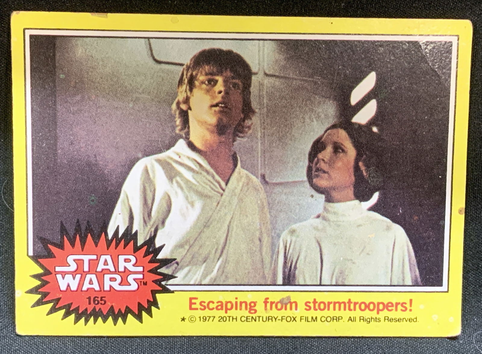 1977 Star Wars #165 Escaping Stormtroopers Card: Vintage 1977 Topps Star Wars trading card, specifically card #165 titled Escaping from stormtroopers. Card features a scene with Luke Skywalker & Princess Leia Organa. Copyright 1977 20th Century-Fox