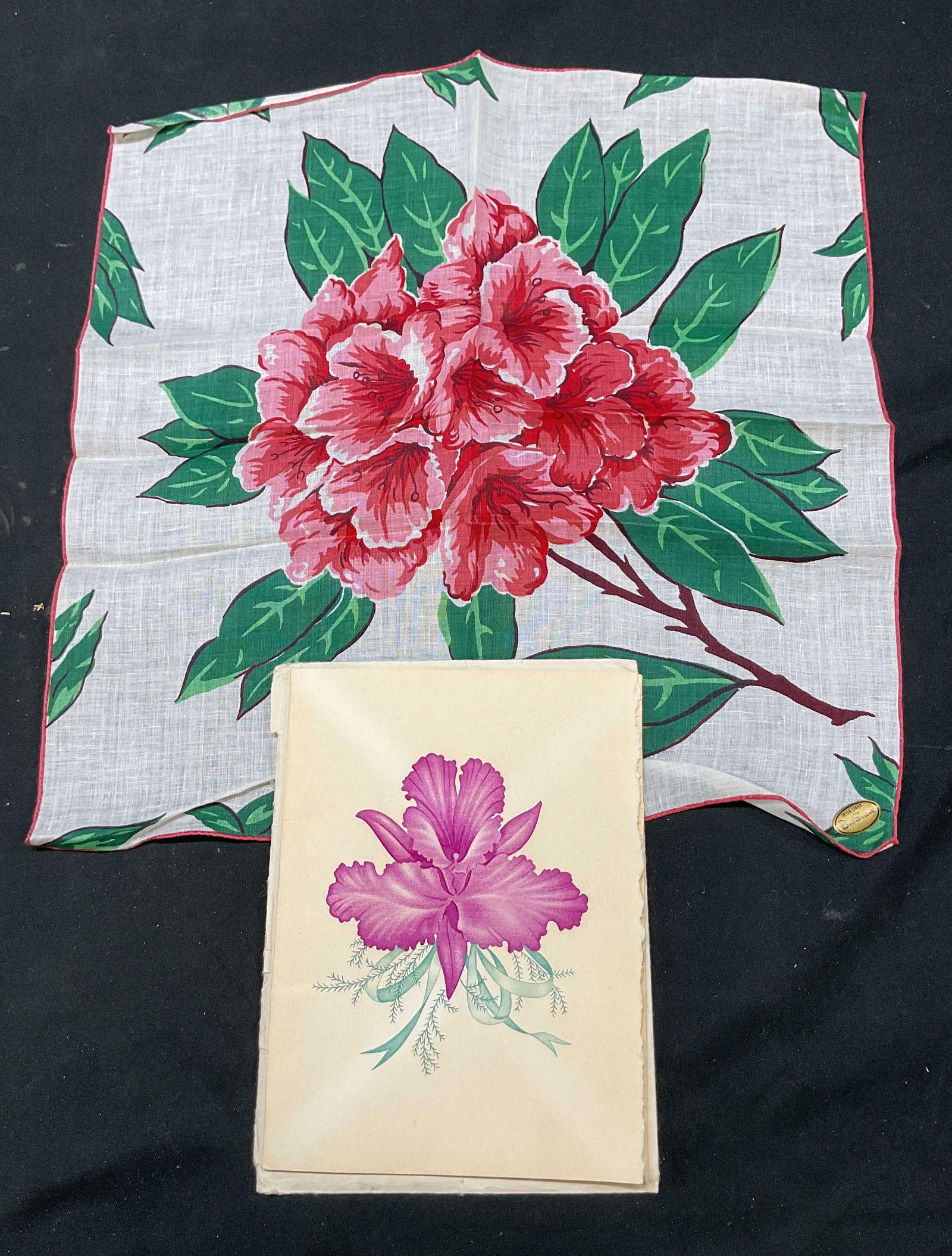 Irish Linen Best Seller Floral Scarf W Envelope: Irish Linen Best Seller floral scarf. Linen material. Scarf reads Irish Linen Best Seller. Pink trim. Floral and leaf motifs in pink, green, and brown. Comes in a card with envelope. Card reads Munyer