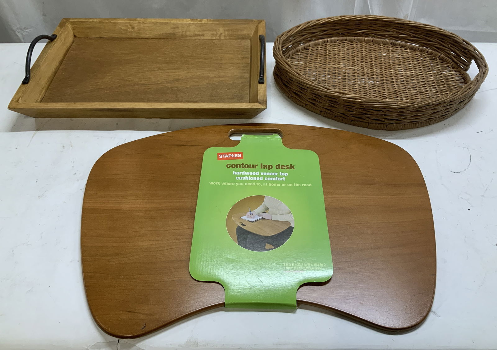 Lot 3 Wooden Serving Trays & Lap Desk WINSOME+: Lot includes, 1 Winsome wooden serving tray with metal handles, 1 rattan serving tray & 1 Staples wooden contour lap desk. Pieces vary in size. Signed & marked. Reads, WINSOME WOOD & STAPLES. Surface