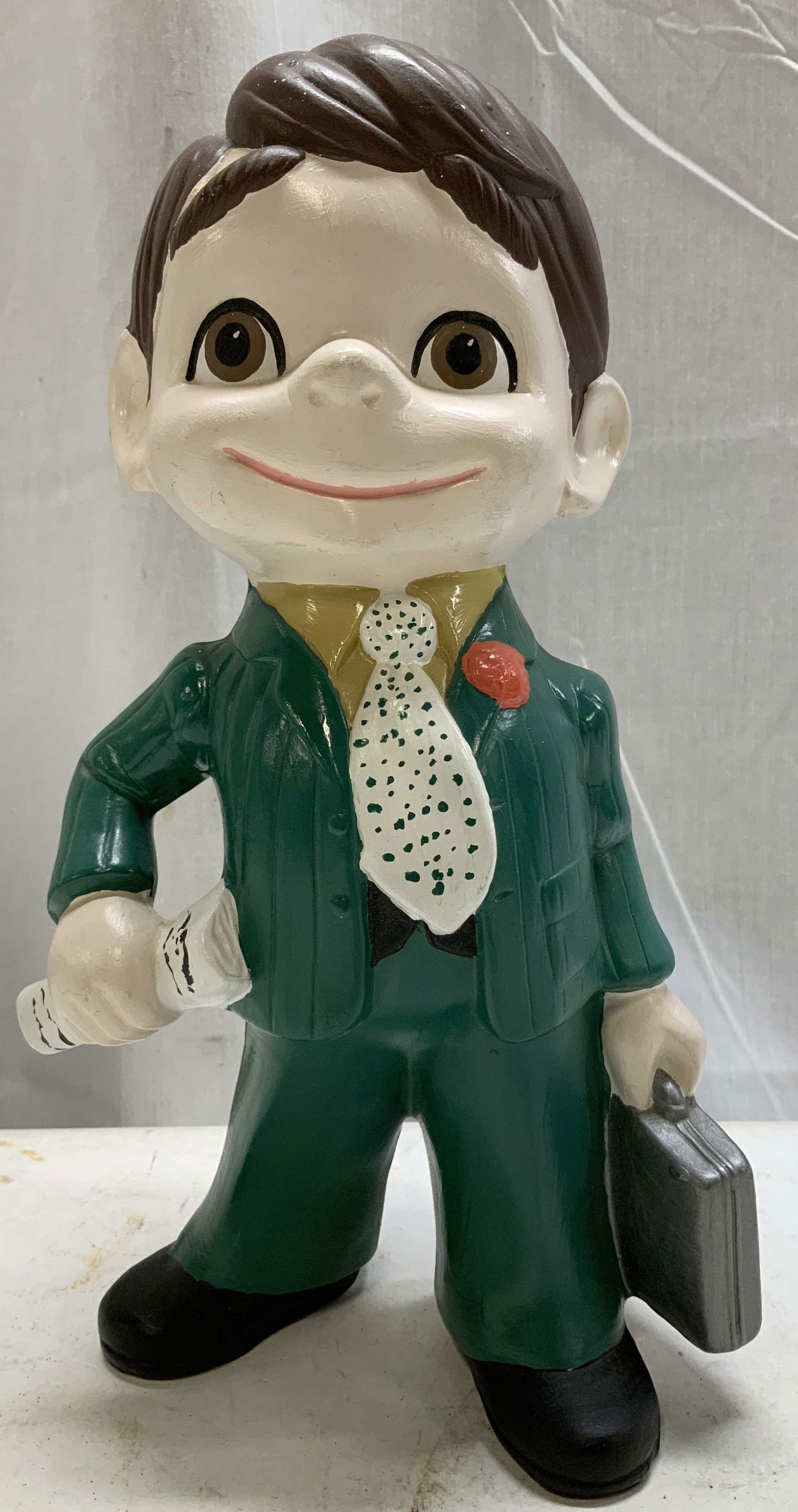 Hand Painted Jolly Green Giant Ceramic Figurine: Jolly green giant ceramic figurine features hand painted accents. Shades of brown, red, yellow & green. Fig is holding a suitcase that reads, J.O.L. Jolly Green Giant. Surface wear consistent to age,