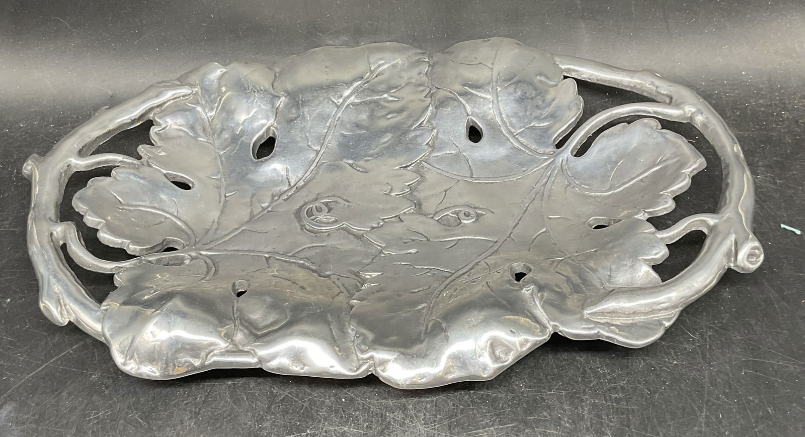 Vintage Silver Tone Leaf Vine Serving Tray: Vintage silver tone metal serving tray with embossed leaf and vine motif. Possibly pewter or aluminum. Measures approx. 14 x 9 inches. Some scratching. Serving tray, silver tone tray, leaf tray, vine