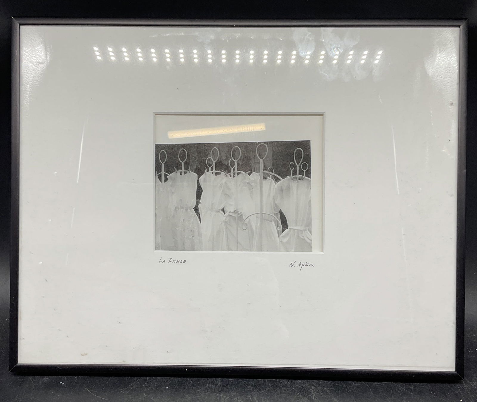 Signed N Apkon La Danse Fine Art Print: Framed and matted black and white fine art print. Signed on the mat N Apkon. Titled La Danse. Dresses on mannequins. Black frame. Not examined out of frame. Frame measures approx. 11.25 x 14.25 inches